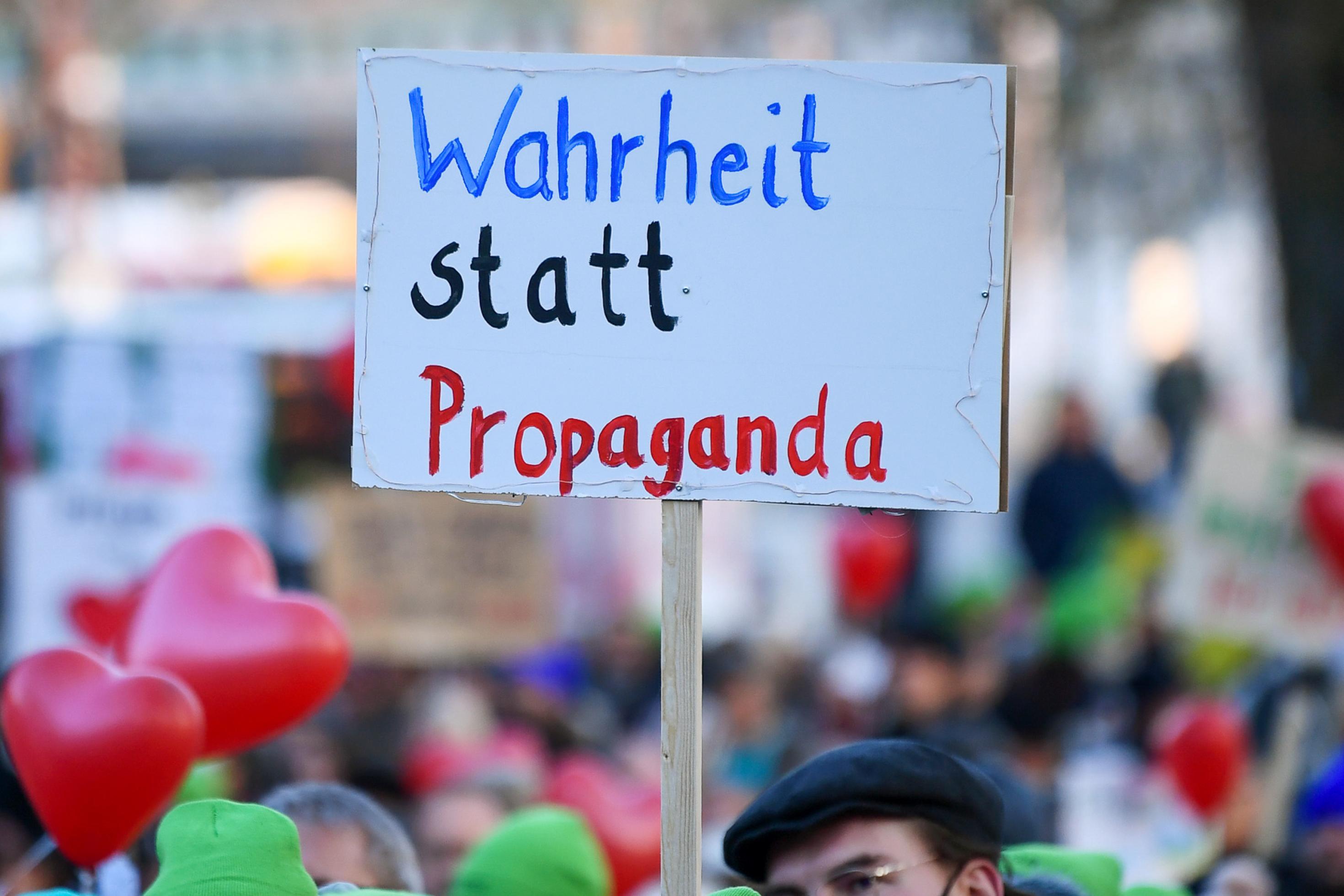Demonstranten halten ein Schild mit der Aufschrift „Wahrheit statt Propaganda“ hoch.