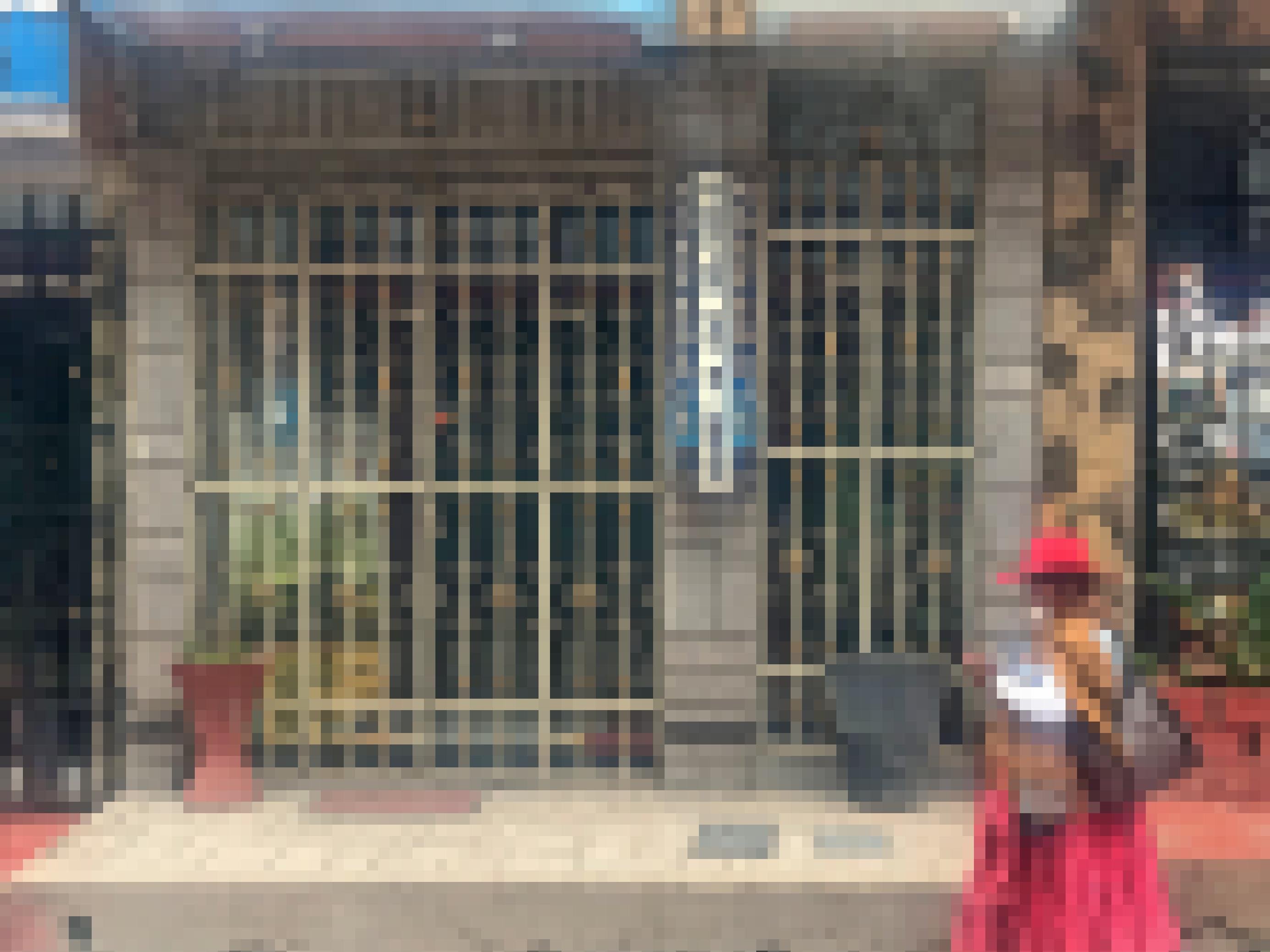 Das Bild zeigt eine Frau in traditioneller peruanischer Kleidung mit Mundschutz, die auf der Straße an einem Laden vorbeigeht.