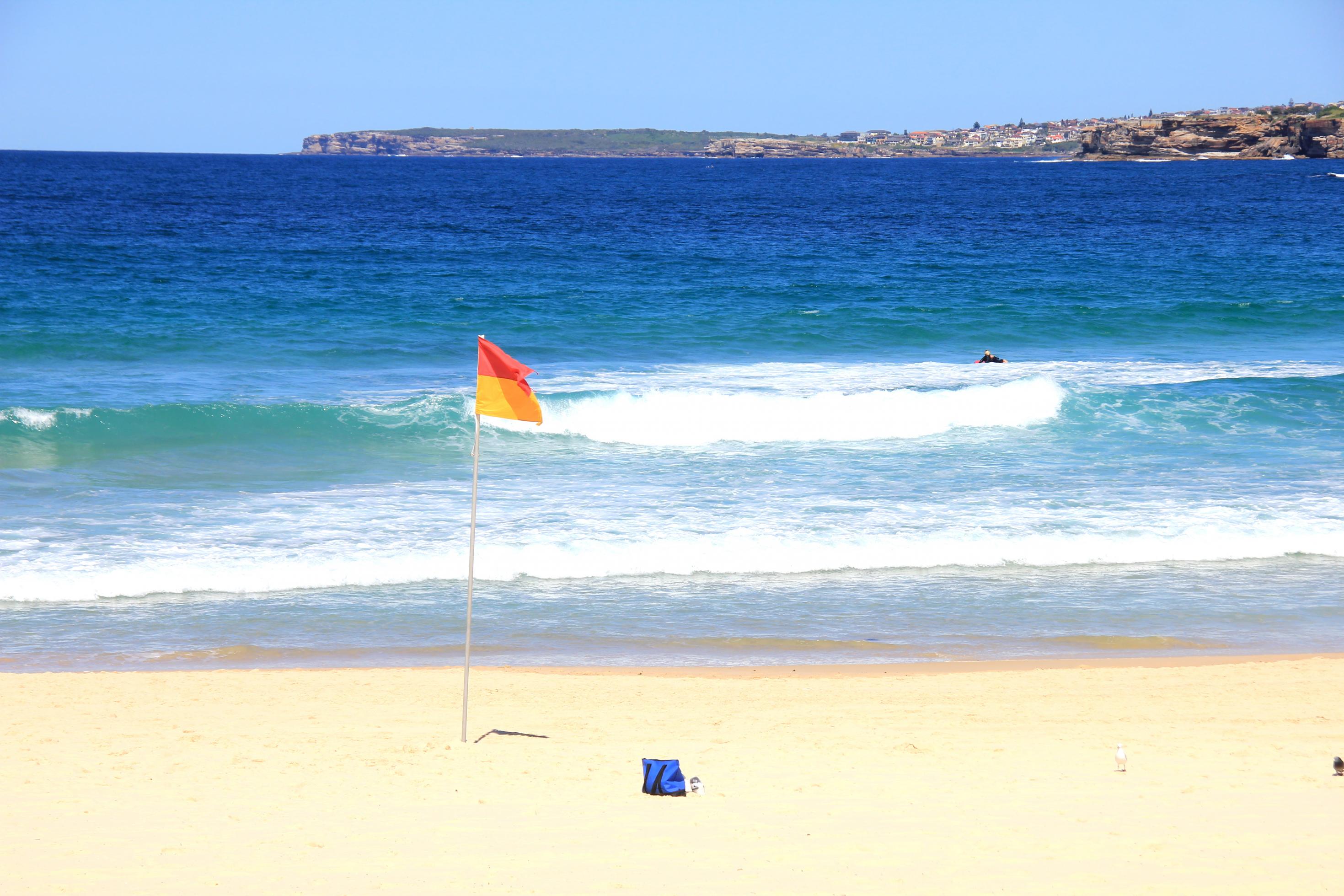 Eine gelb-rote Lifesaver-Flagge weht vor dem weitgehend menschenleeren Strand von Bondi Beach in Sydneys Osten