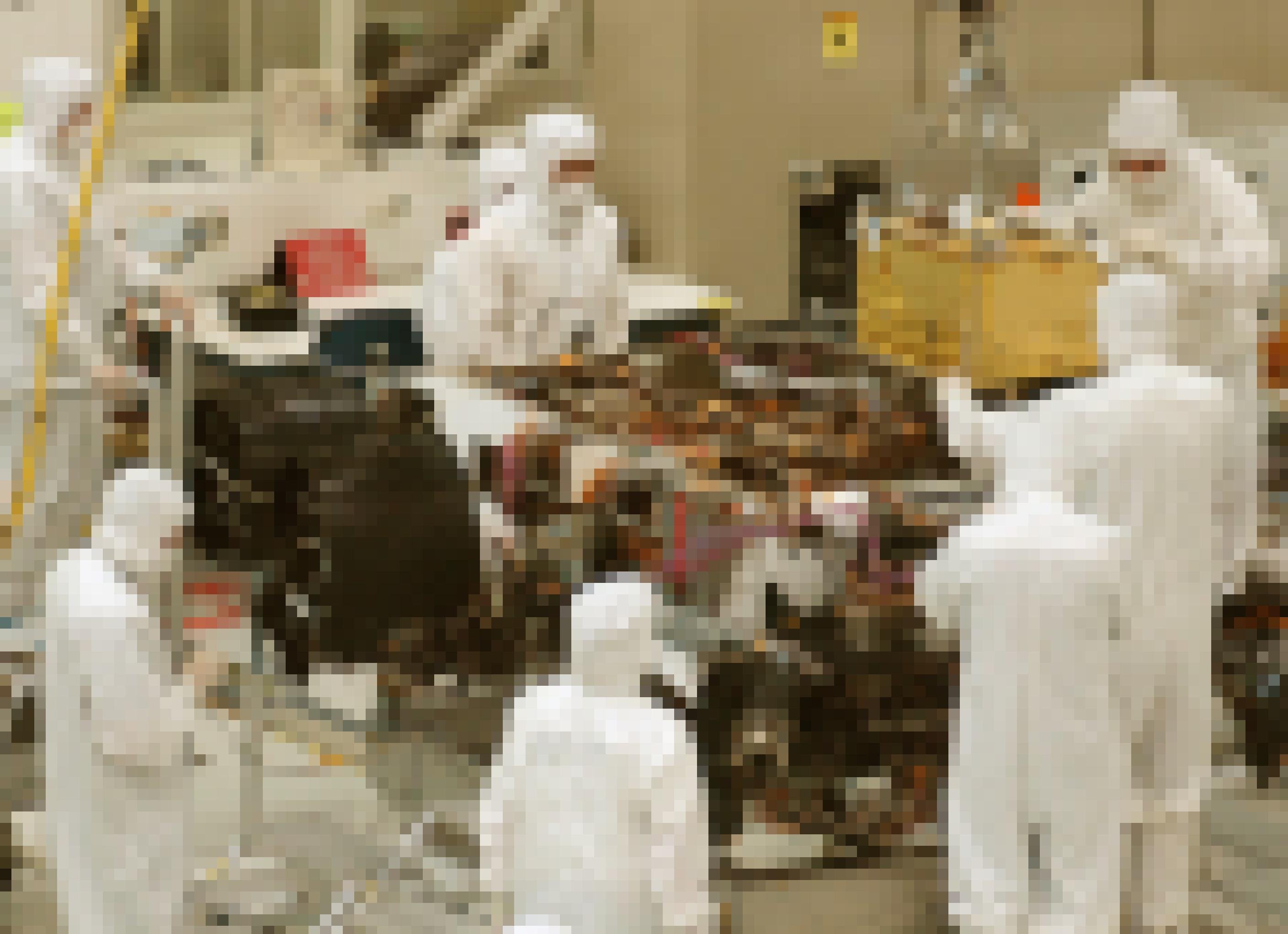 In einem Reinraum, in dem mehrere Arbeiter in weißen Vollschutzanzügen stehen, wird in den noch offenen Rover Curiosity, mit vielen frei liegenden Kabeln und Komponenten, eine Mikrowellen-große Box in den Rover abgesenkt.