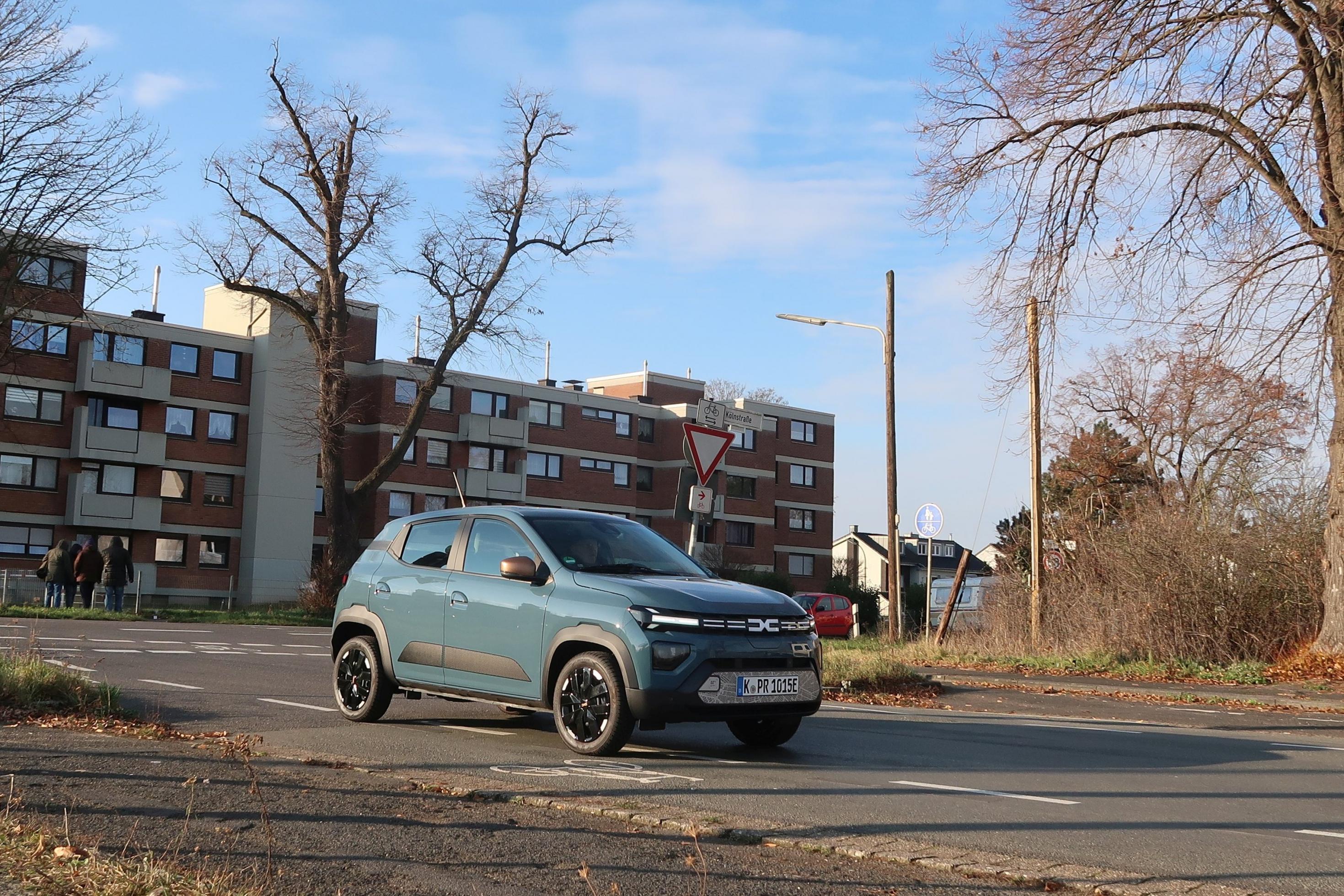Dacia Spring fährt durch ein Wohngebiet.