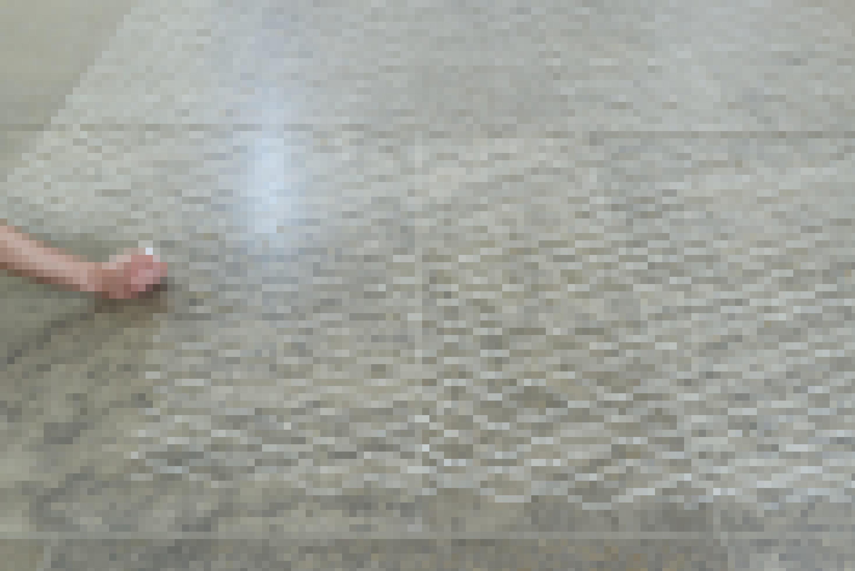 Foto eines Bodens aus glatten Steinplatten. Darauf ist ein Netzmuster mit weißer Kreide gemalt. Links im Bild sieht man eine Hand mit Kreide, welche das Muster weiterführt.