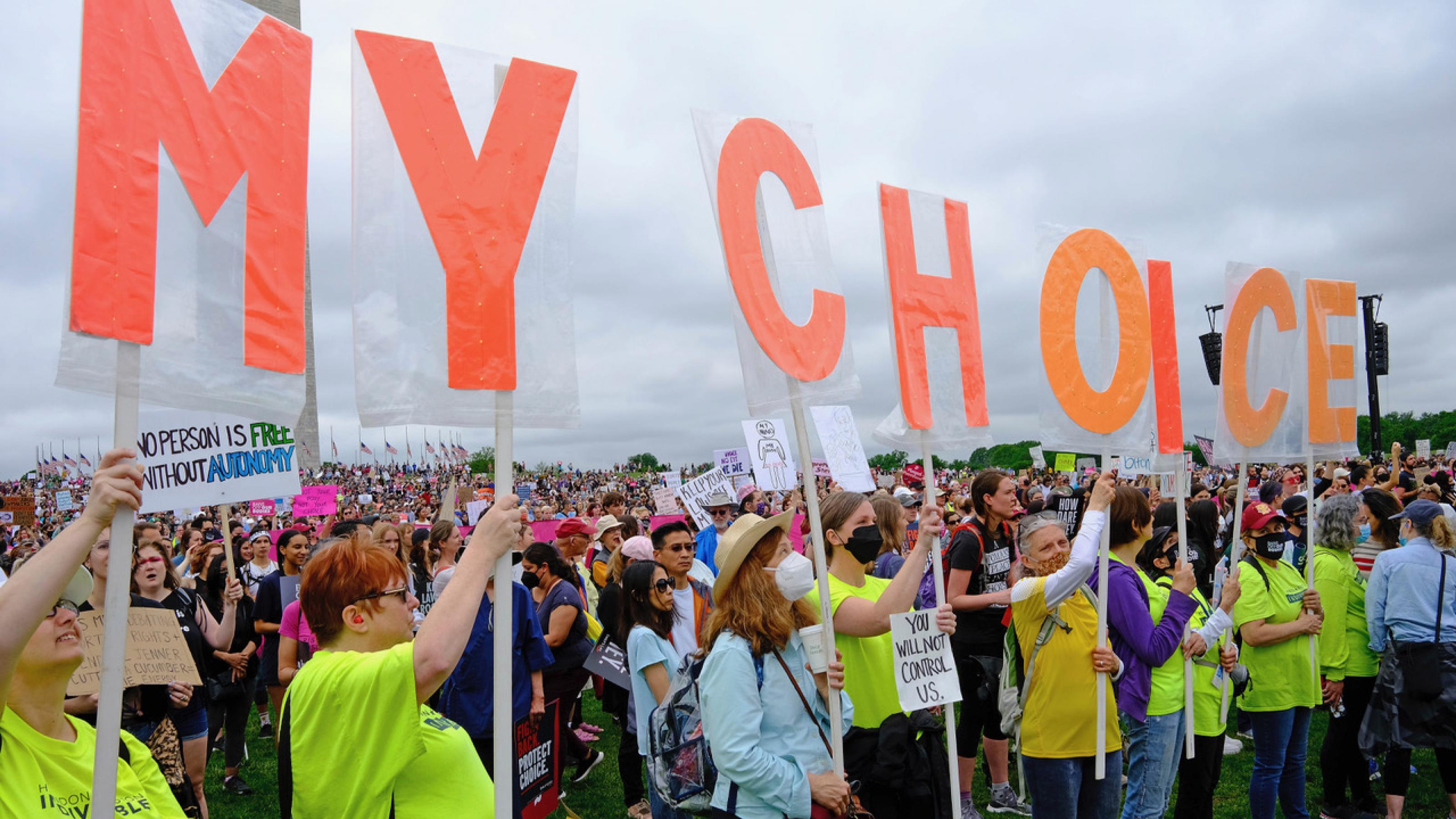 Demonstrierende halten Plakate mit Buchstaben in die Höhe, die zusammen den Satz „My Choice“ ergeben.