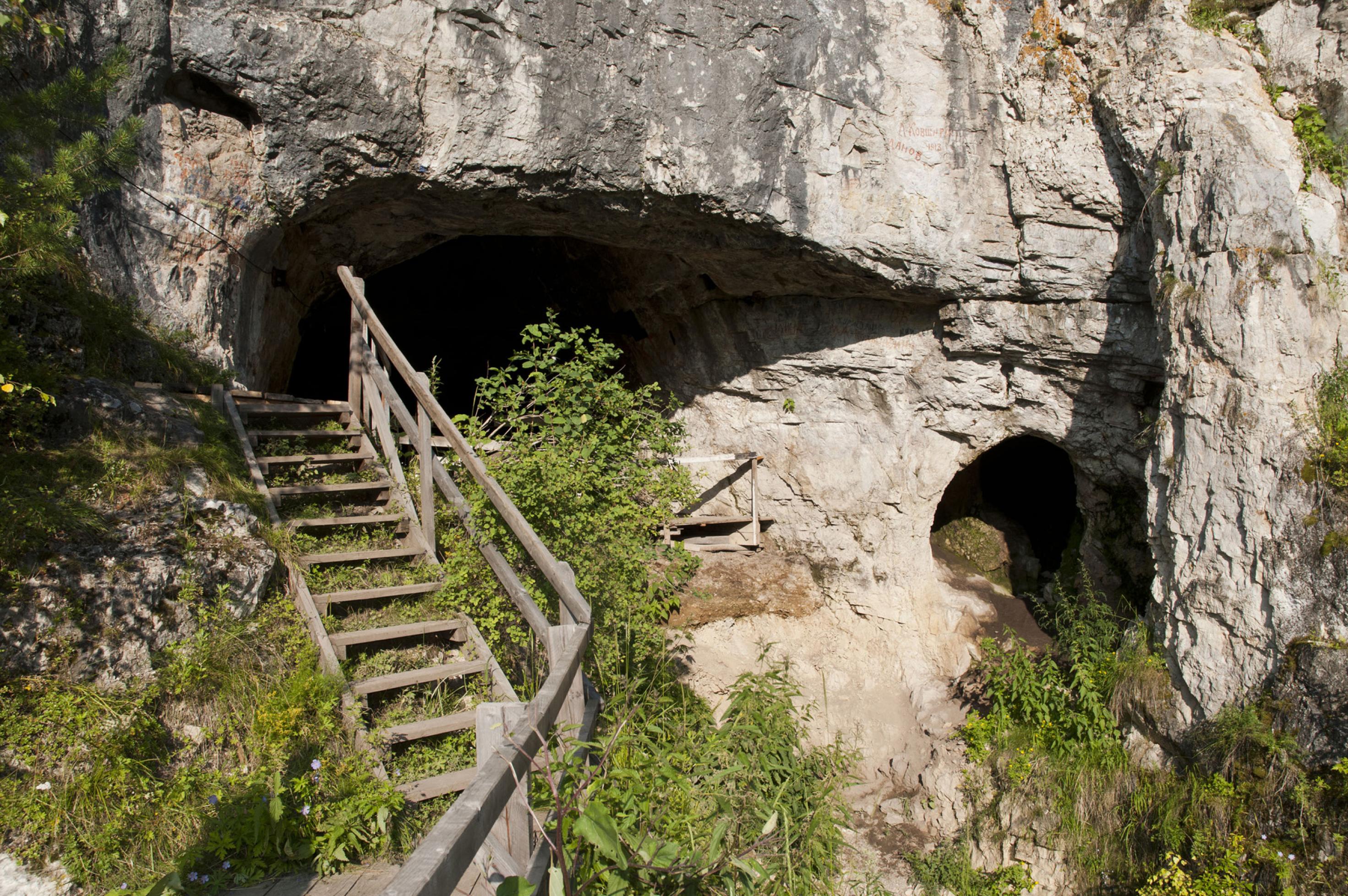 Das Foto zeigt den äußeren Eingangsbereich der Denisova-Höhle in Sibirien, vor dem die Forscher eine Holztreppe errichtet haben, um leichter hinein zu gelangen. In der Höhle hatte einst ein bislang unbekannter Verwandter des Homo sapiens gelebt: der Denisova-Mensch. Erst im Jahr 2009 hatten Forscher ihn anhand der Erbsubstanz eines winzigen Knochenstückes identifiziert.