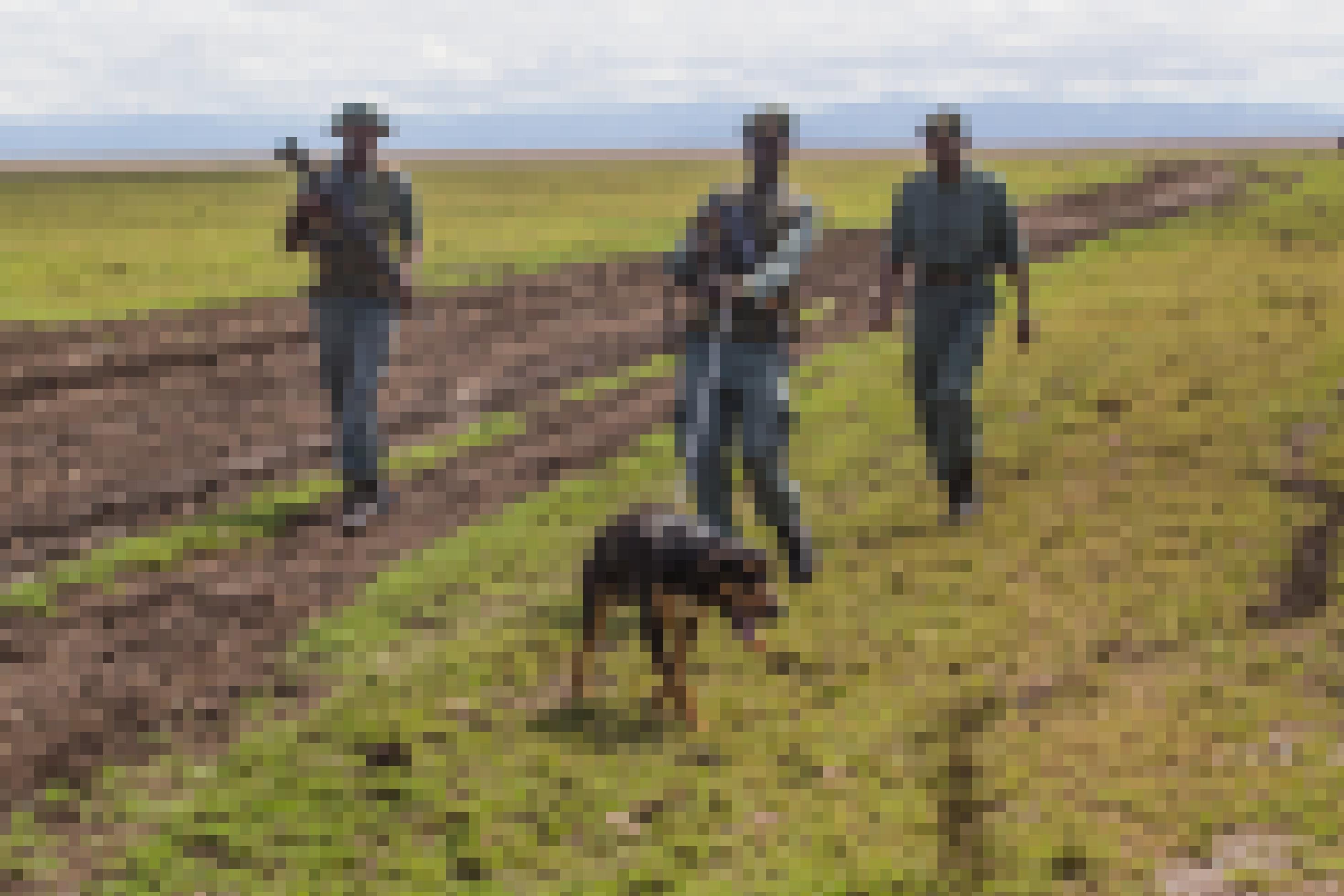 Drei kenianische Ranger eilen hinter dem Spürhund Niamusi her, der einer Fährte folgt