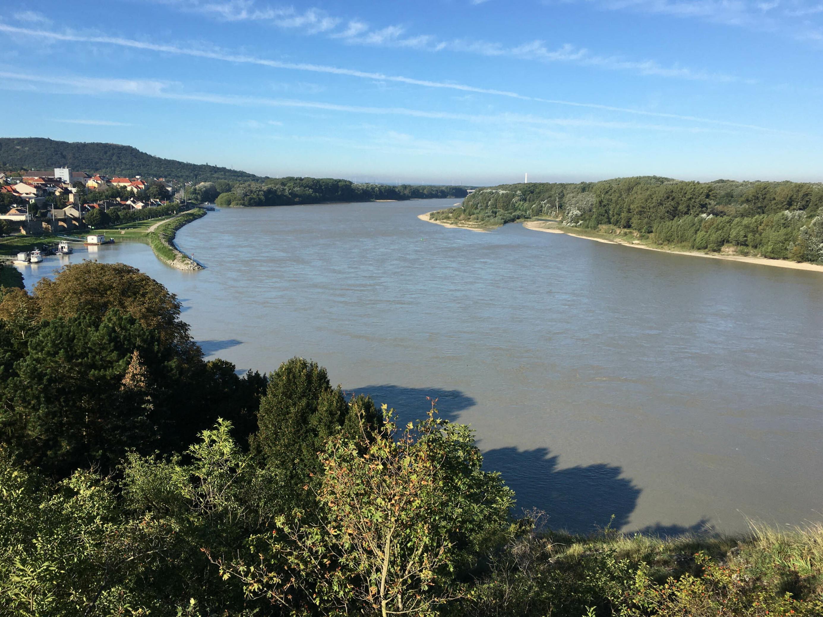 Fluss mit Umland, flussaufwärts blickend, links ein paar Häuser einer historischen Stadt.