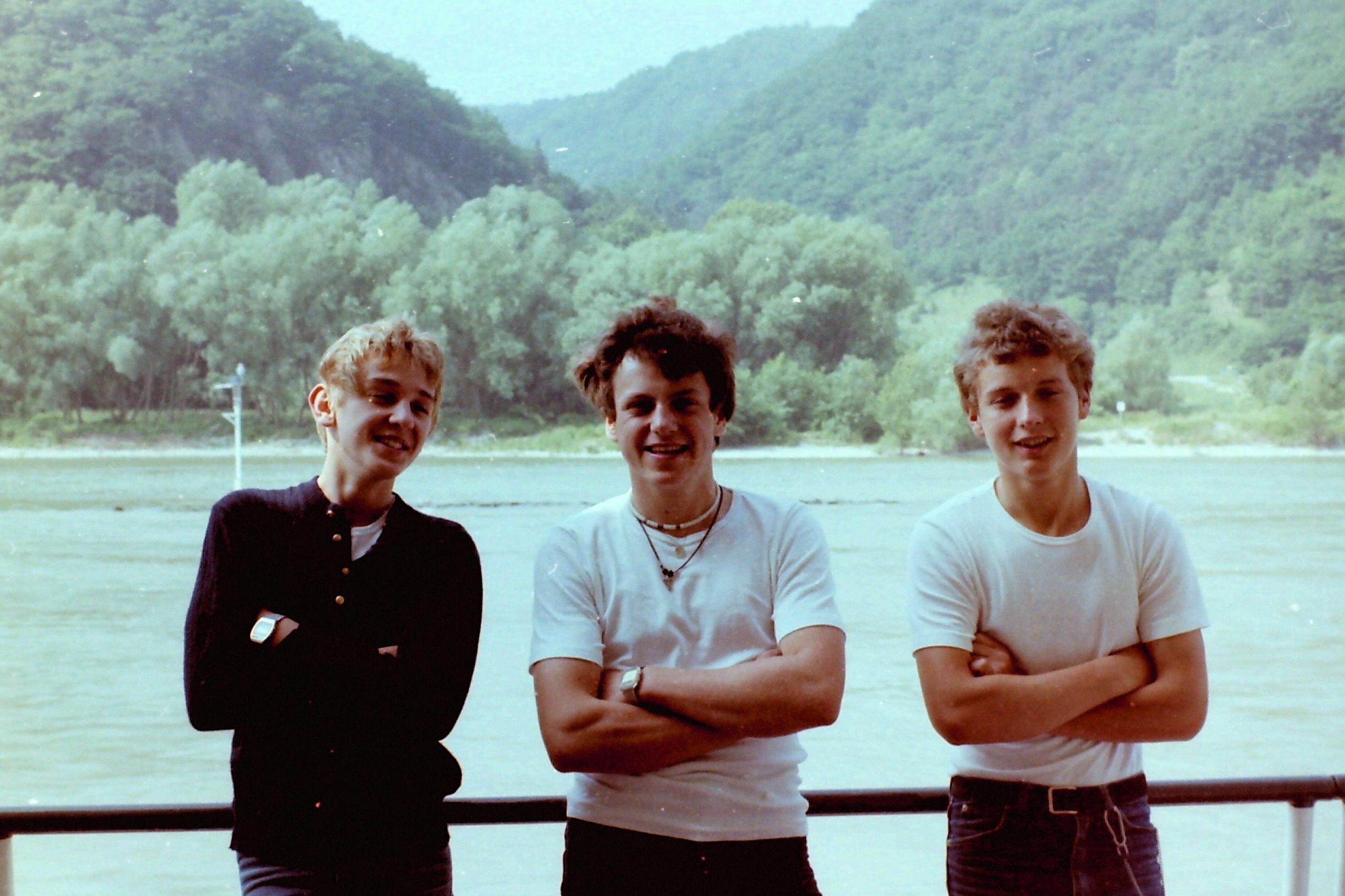 Drei junge Männer in Matrosenkleidung auf einem Schiff.