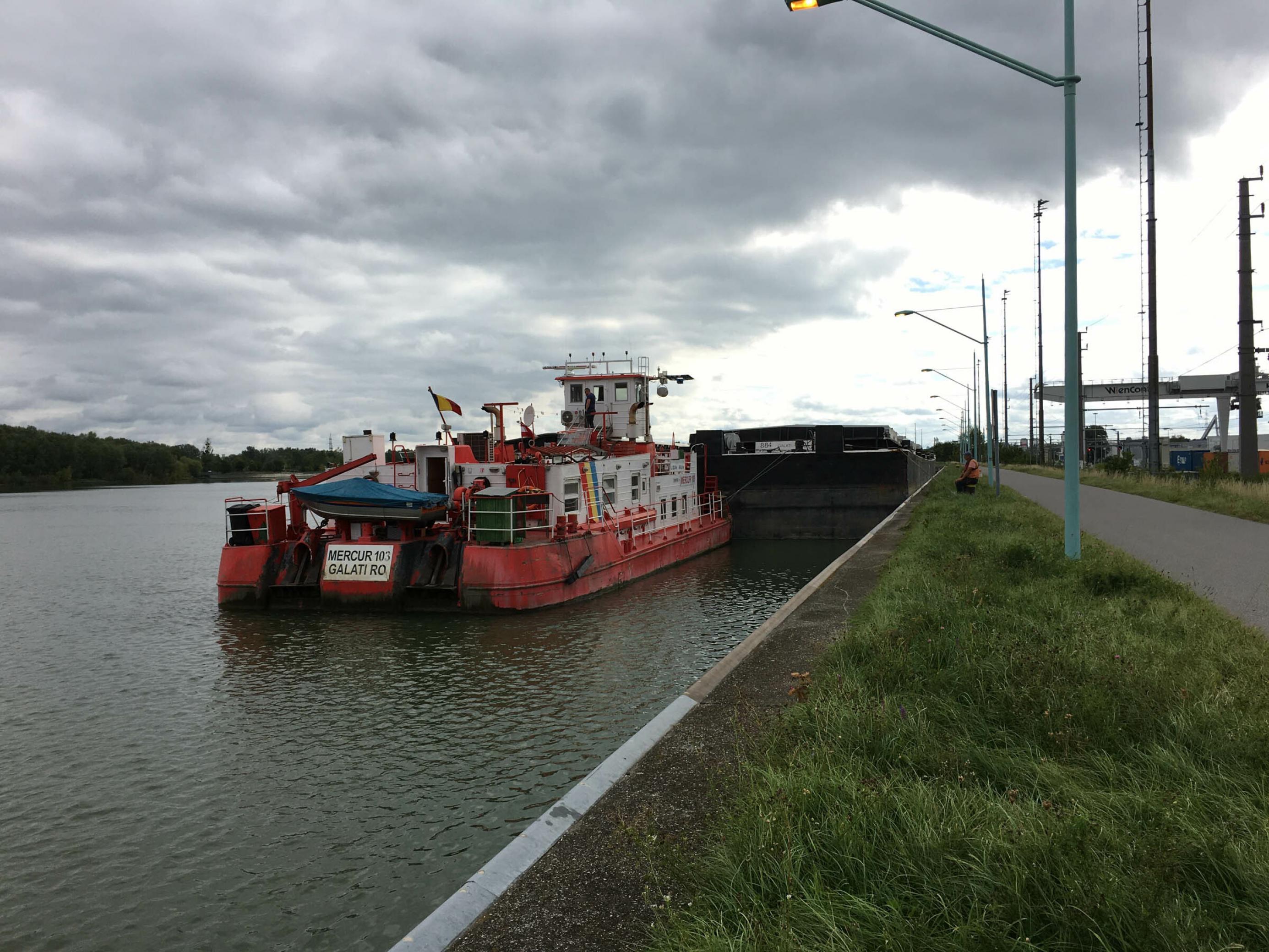 Kleines rotes Frachtschiff steht am Ufer des Flusses.