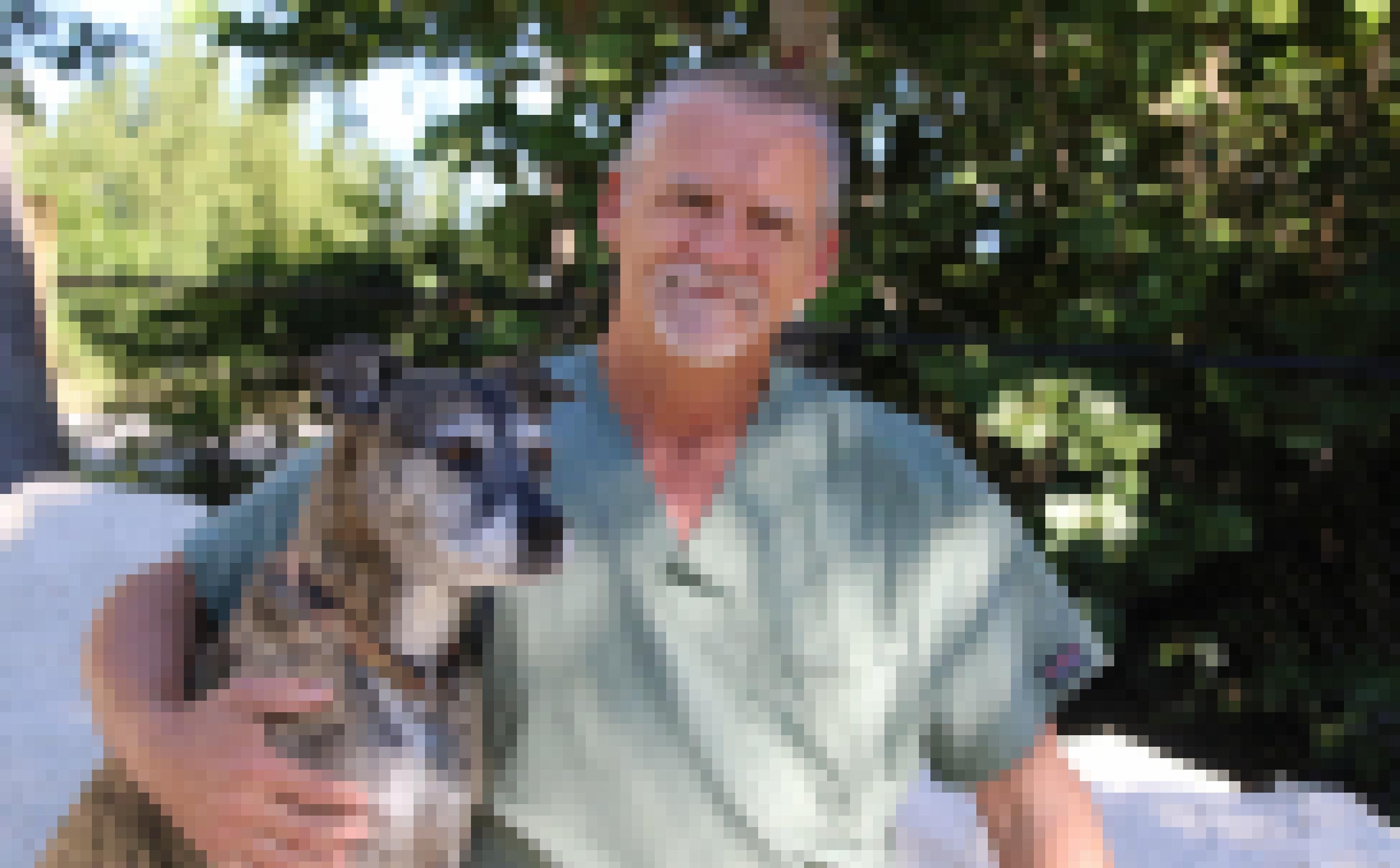 Tierarzt Doug Mader im Kittel mit Hund neben sich