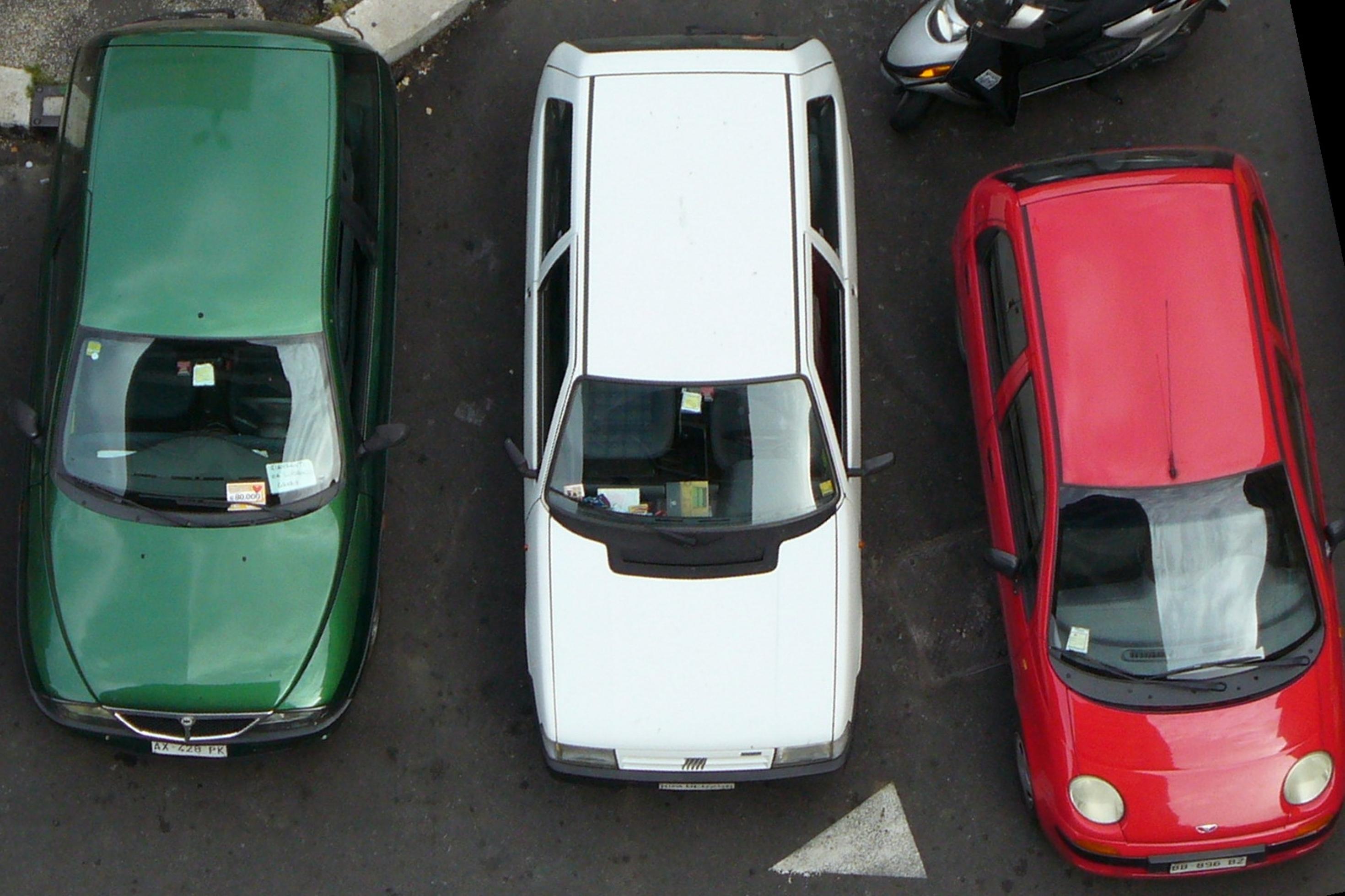 Ein grünes, ein weißes und ein rotes Auto aus der Vogelperspektive.
