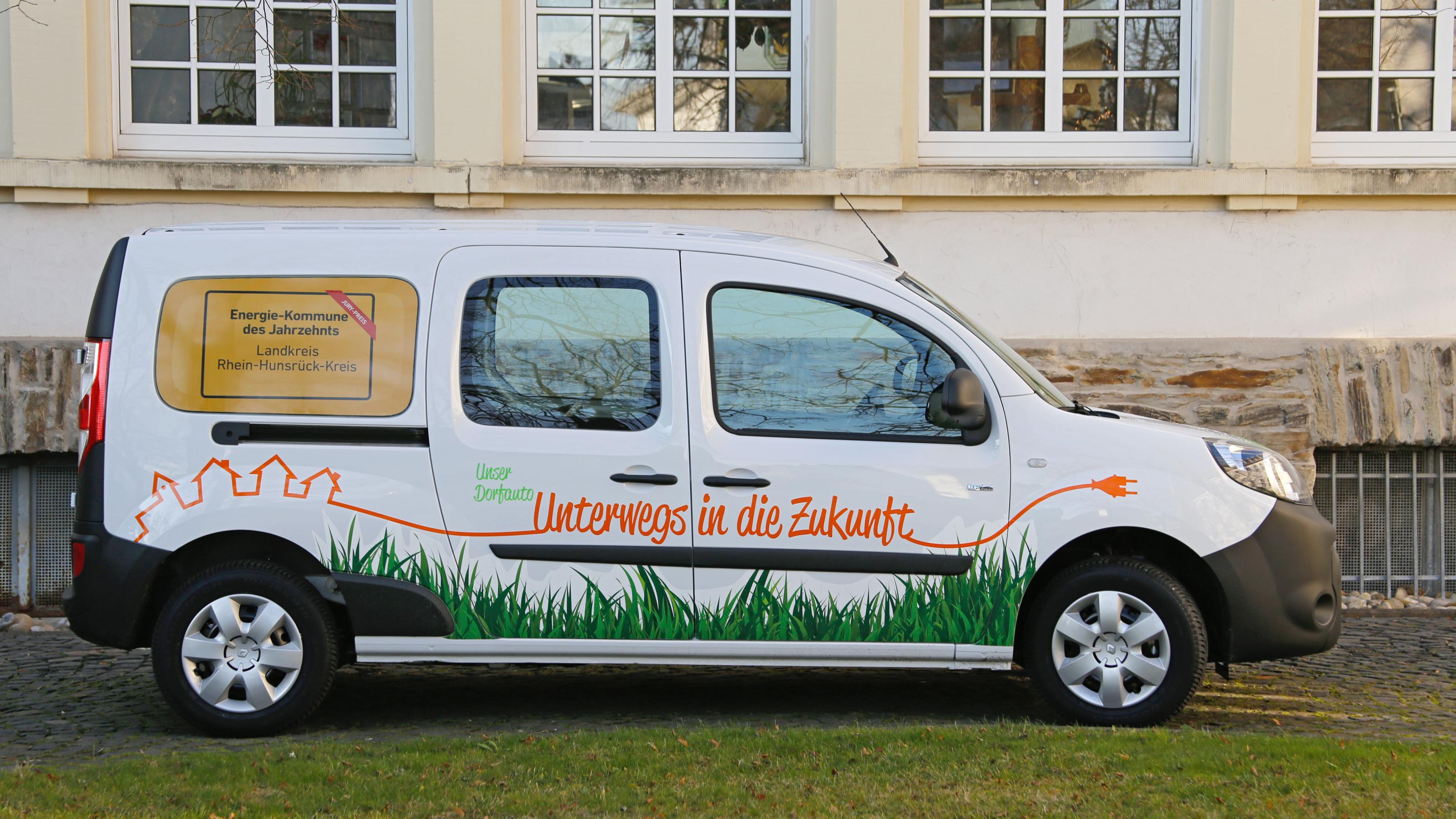 Das Bild zeigt einen Renault Kangoo Maxi, einen elektrisch betriebenen Multi-Van. Die Aufschrift besagt „Unterwegs in die Zukunft“.