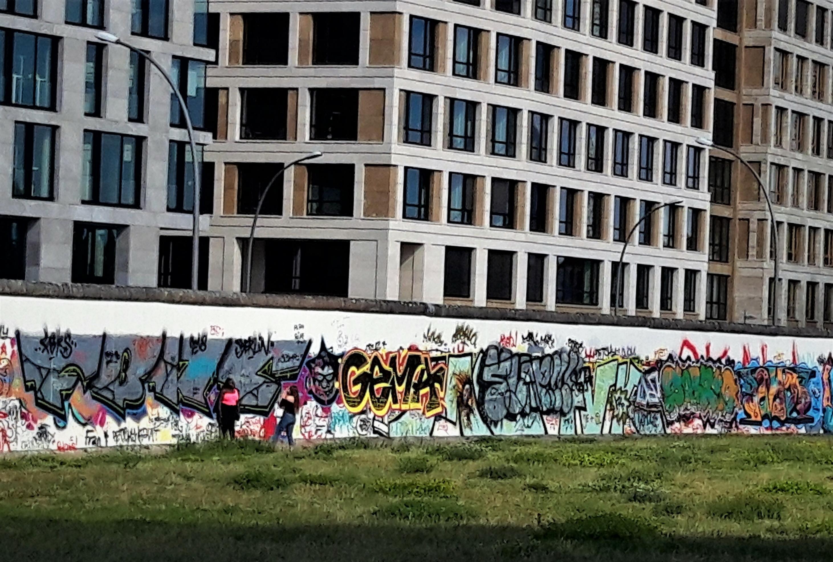 Eine Frau lichtet eine andere vor den Graffiti-überladenen Mauersegmenten der East Side Gallery ab.