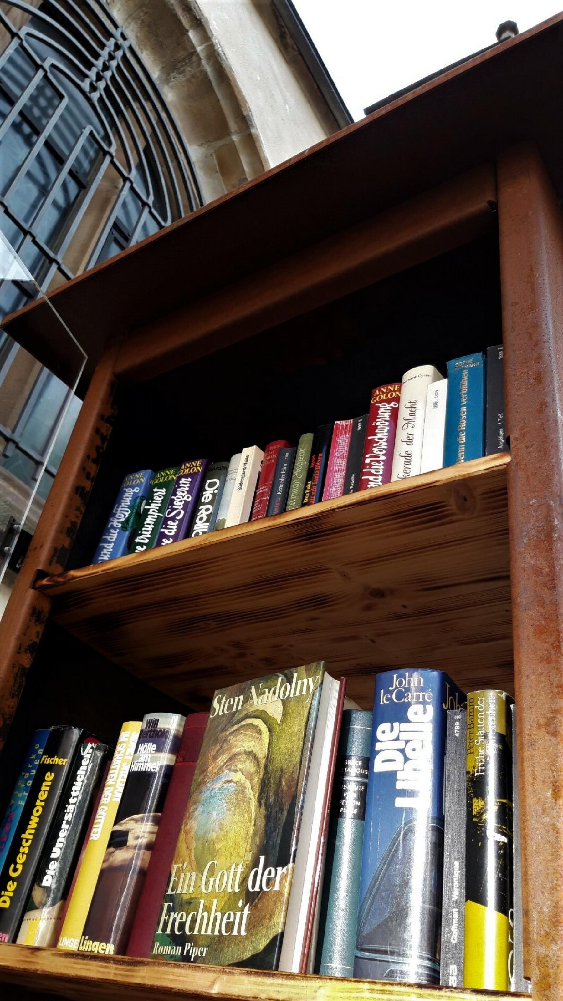 Hinter dem Bücherschrank, auf dem außer dem Nadolny-Cover zwei volle Buchreihen zu sehen sind, lugt ein Stück der Nikolaus-Kirche der Kreuznacher Neustadt hervor.