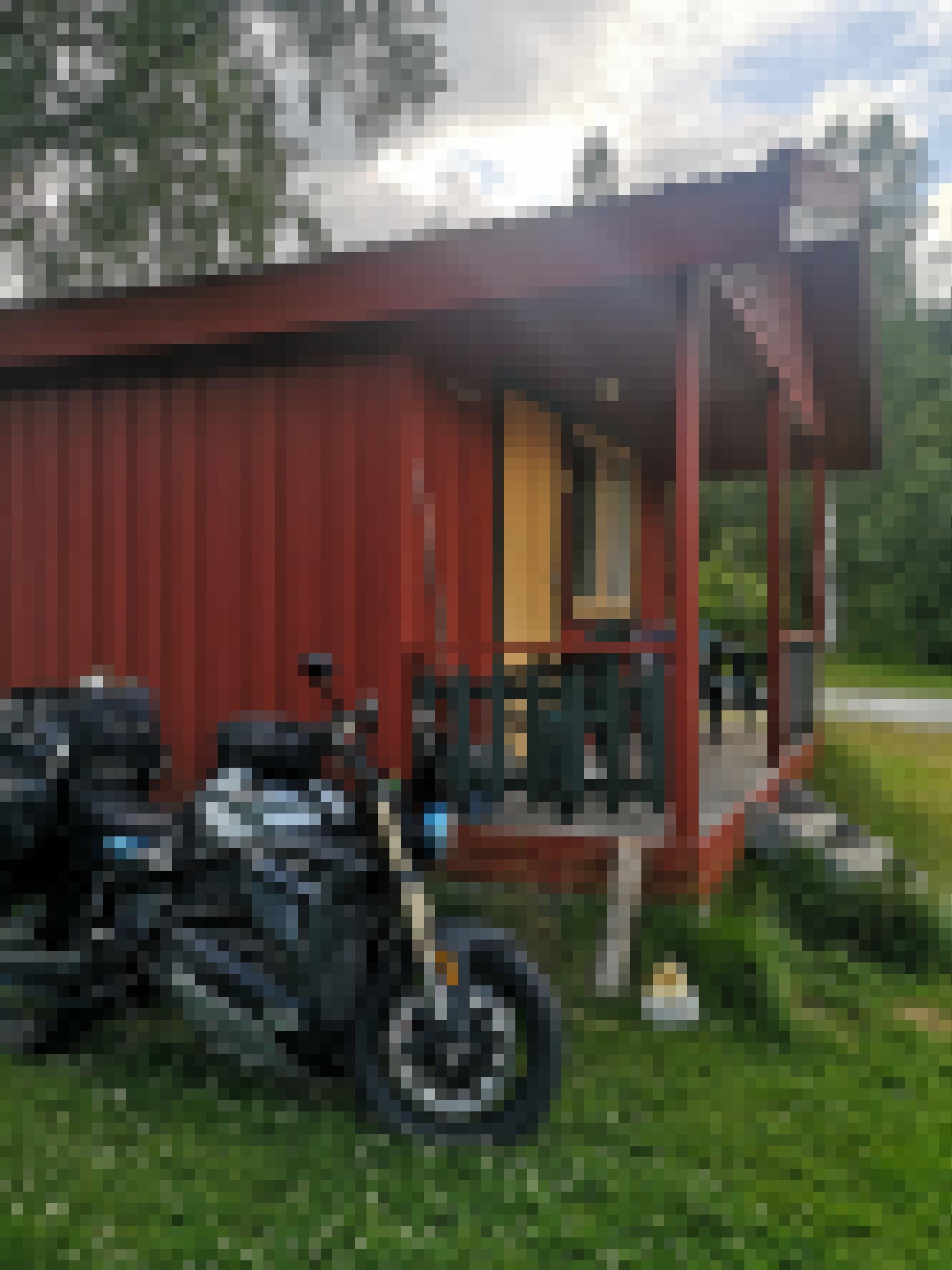 Elektromotorrad parkt vor einer Holzhütte.