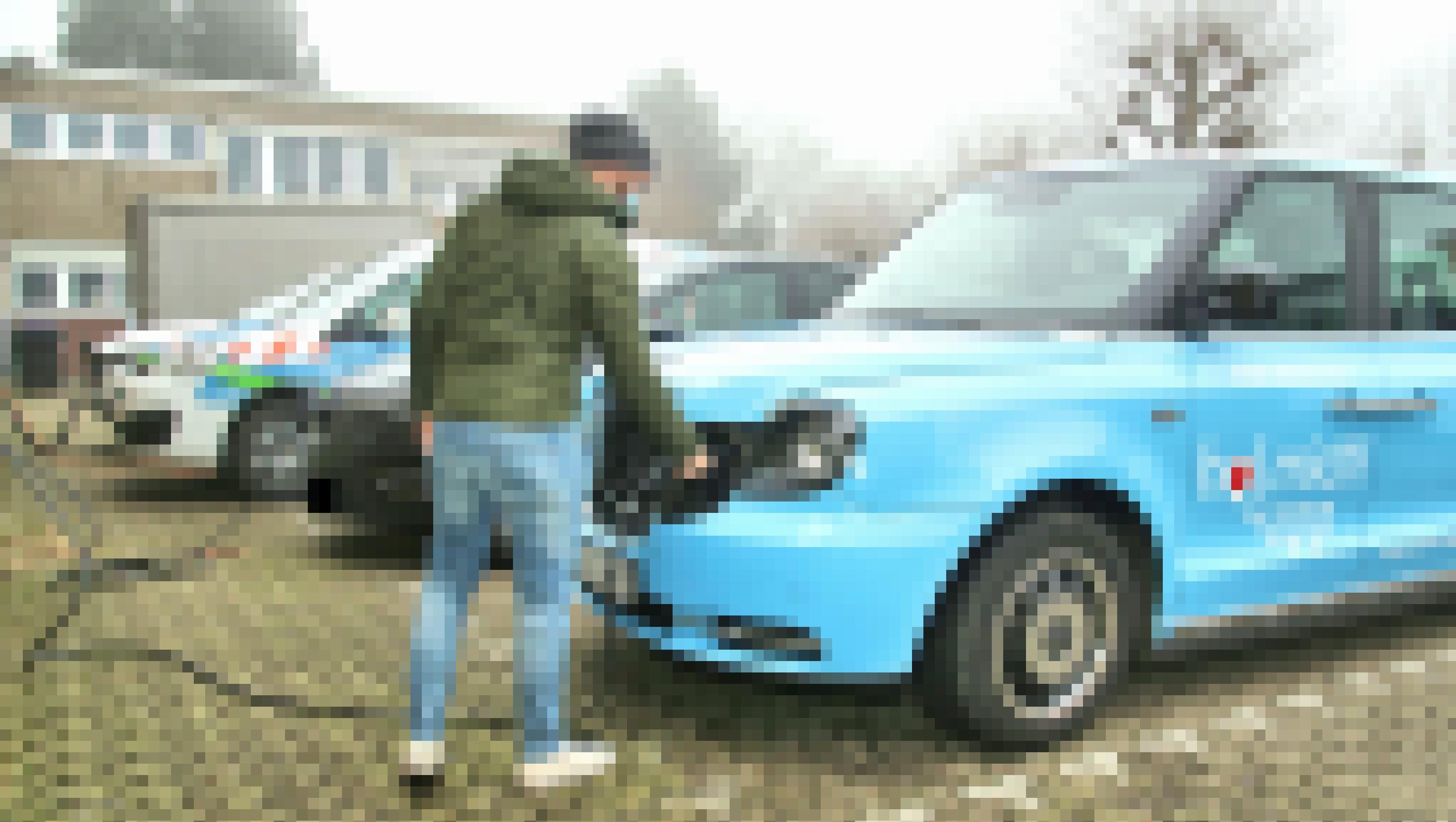 Ein Mann steckt einen Stecker in ein Elektro-Taxi.