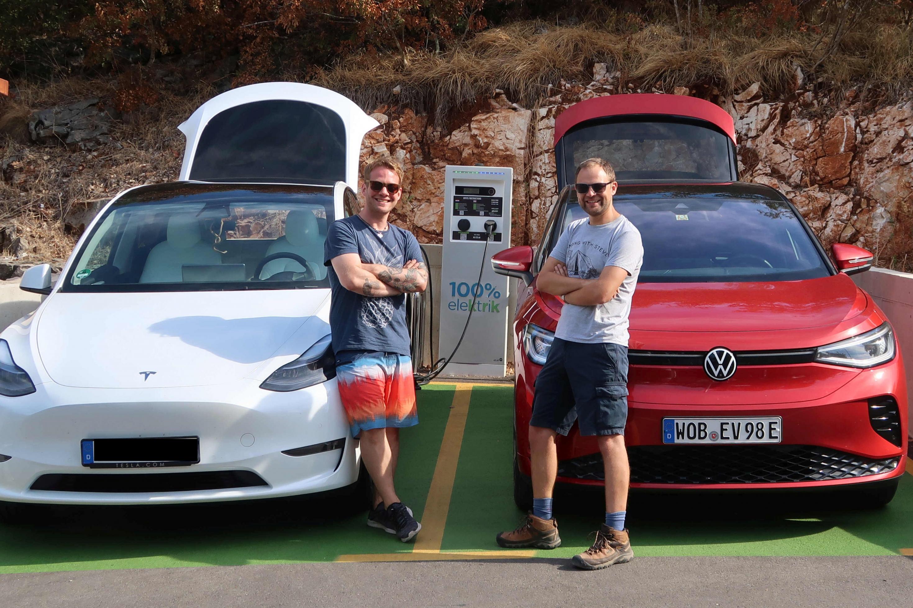 Ein Tesla Model Y und ein VW ID.5 stehen an einer Ladestation, davor die beiden Fahrer.