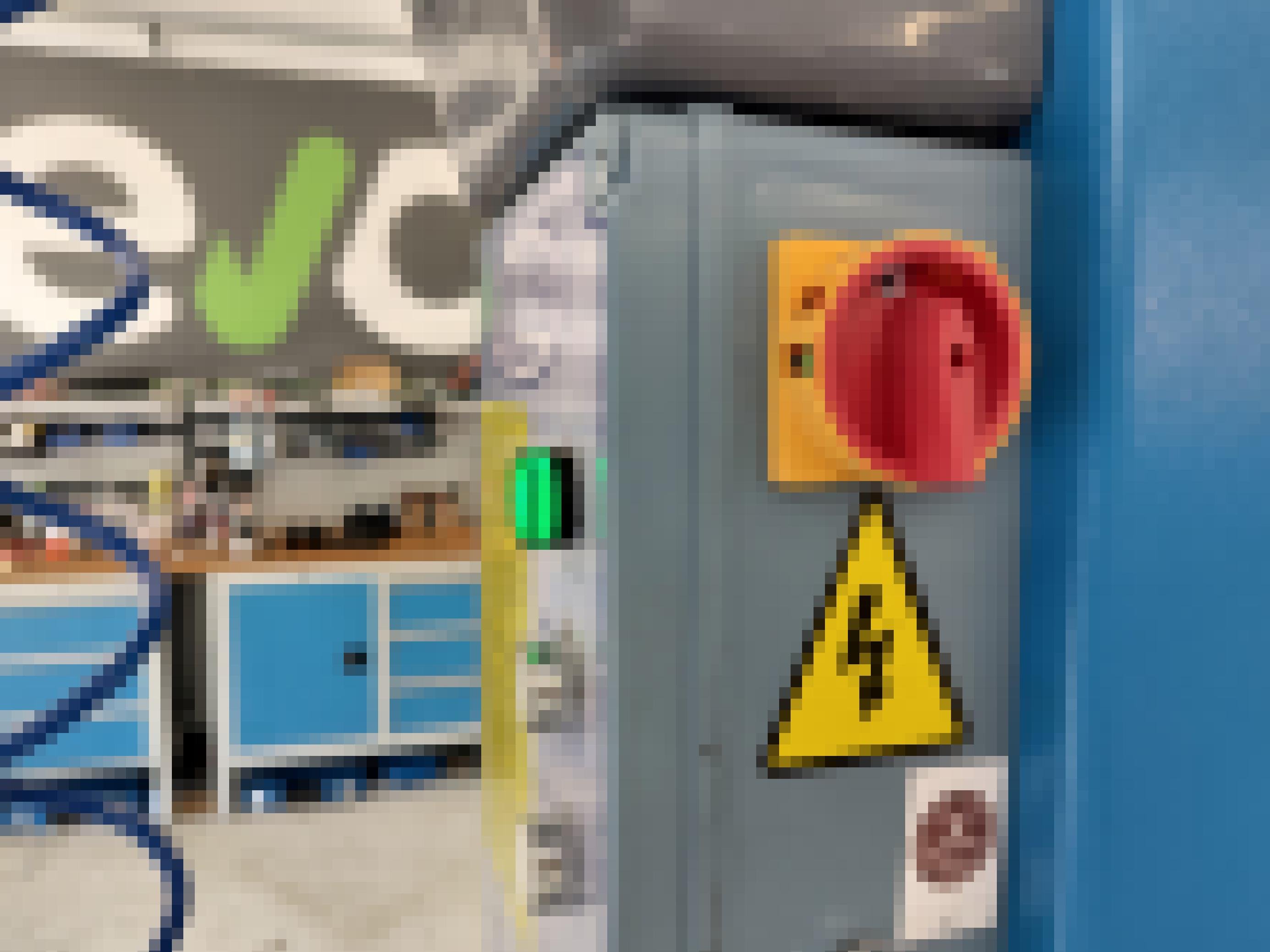 Ein Schild mit gelbem Dreieck und Blitz hängt unter einem Drehschalter.