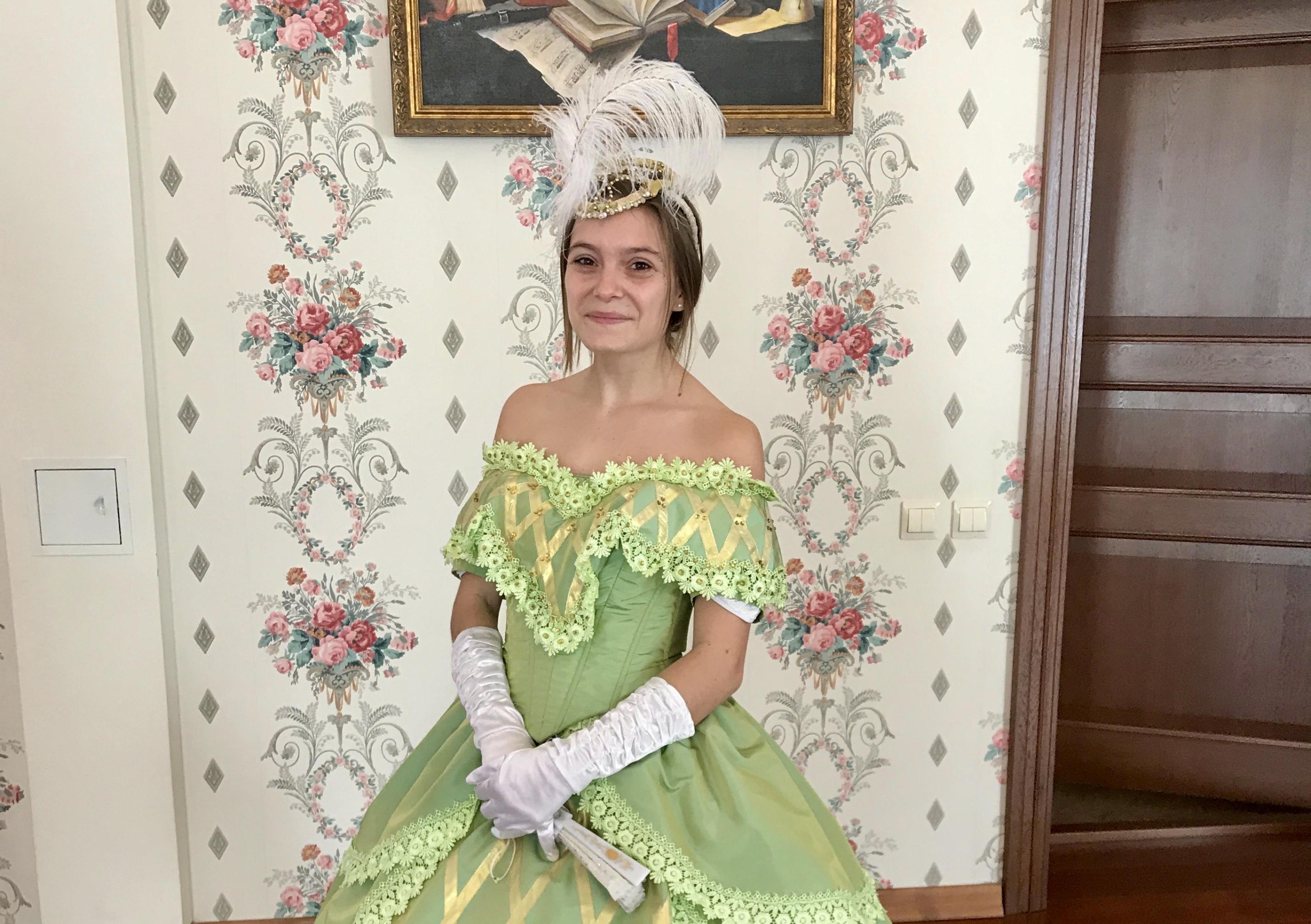 Emma Larson posiert in einem grünen Kleid in altem russischen Stil mit weitem Rock, schulterfreiem Oberteil, und Feder-Tiara an der Universität von Sant Petersburg für einen Ball ihres Geschichtsseminars, 