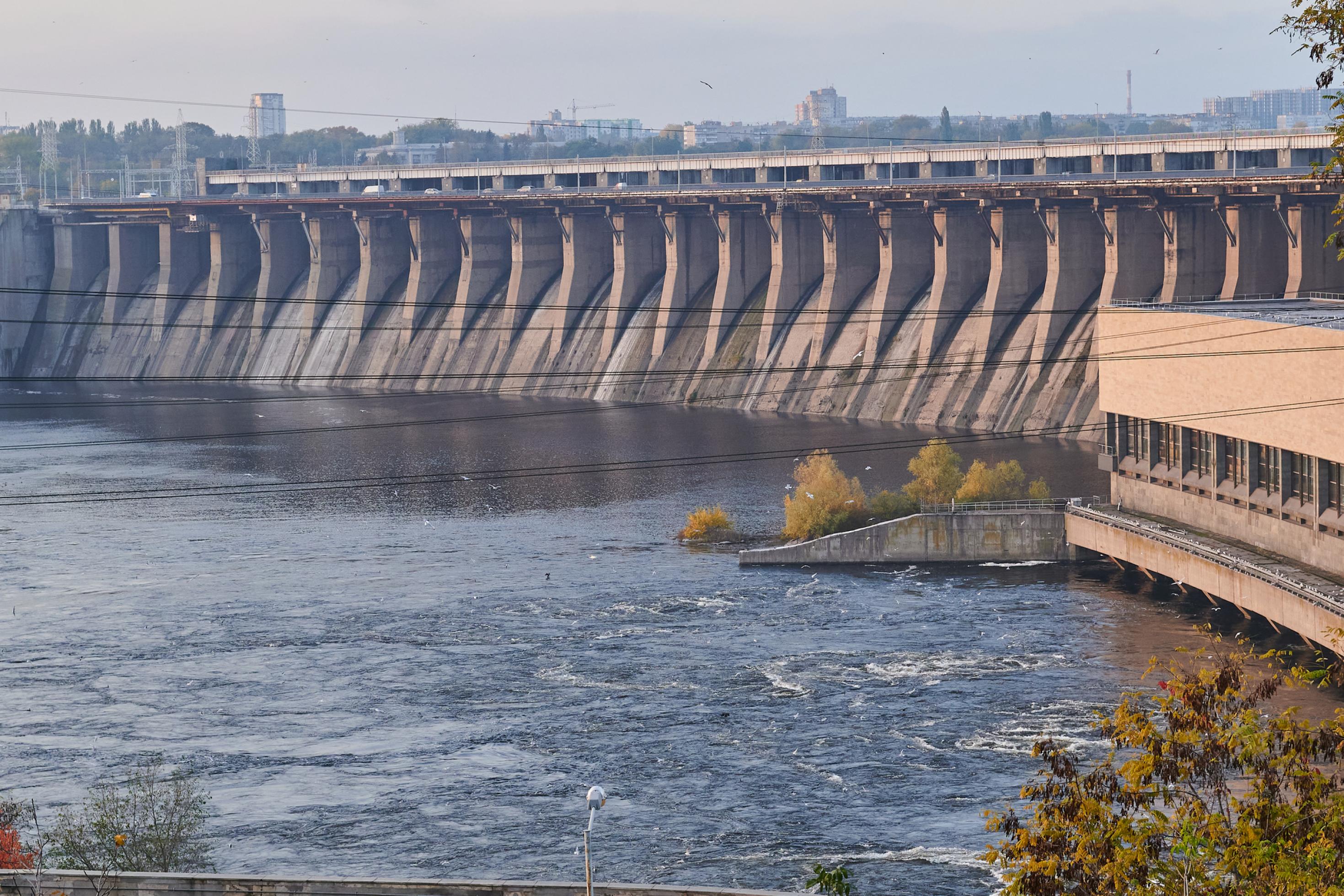 Riesiger Staudamm quer durch großen, breiten Fluss.