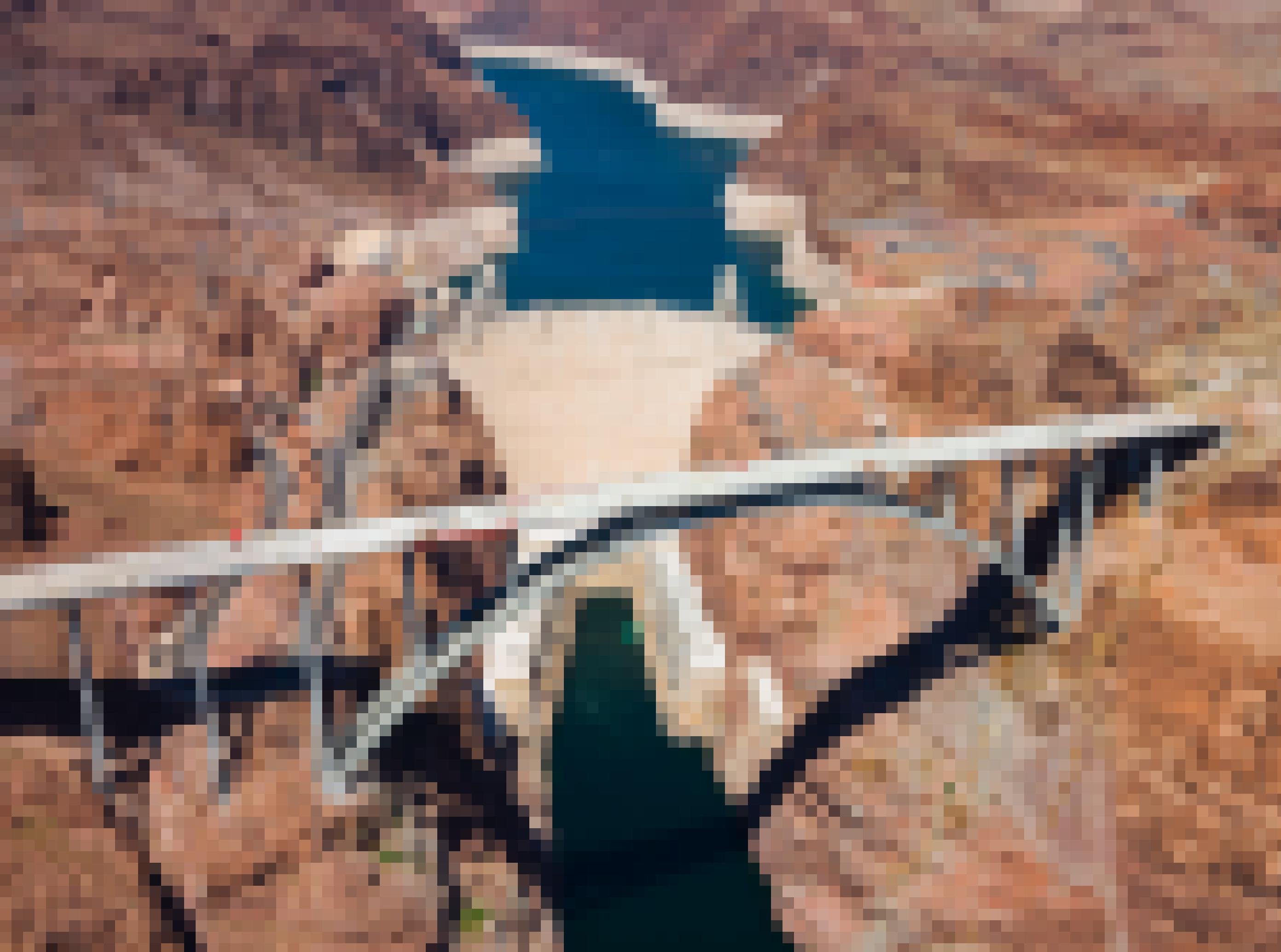 Kupferfarbene Wüstenlandschaft mit tief eingeschnittenem Tal und riesigem Staudamm, davor eine Brücke.
