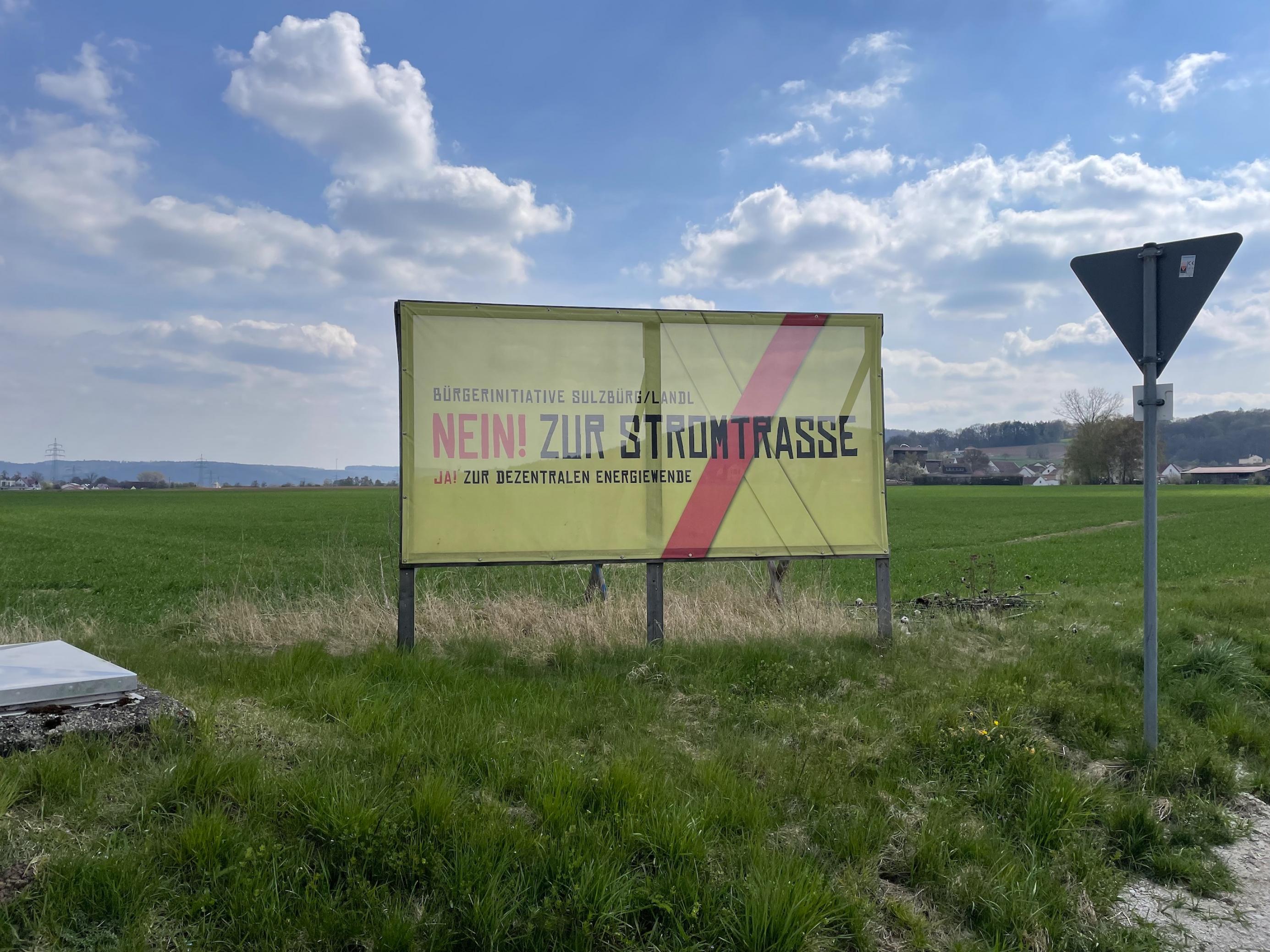 Schild auf freier Landschaft, „Bürgerinitiative Sulzbürg/Landl, Nein zur Stromtrasse, Ja zur Dezentralen Energiewende“
