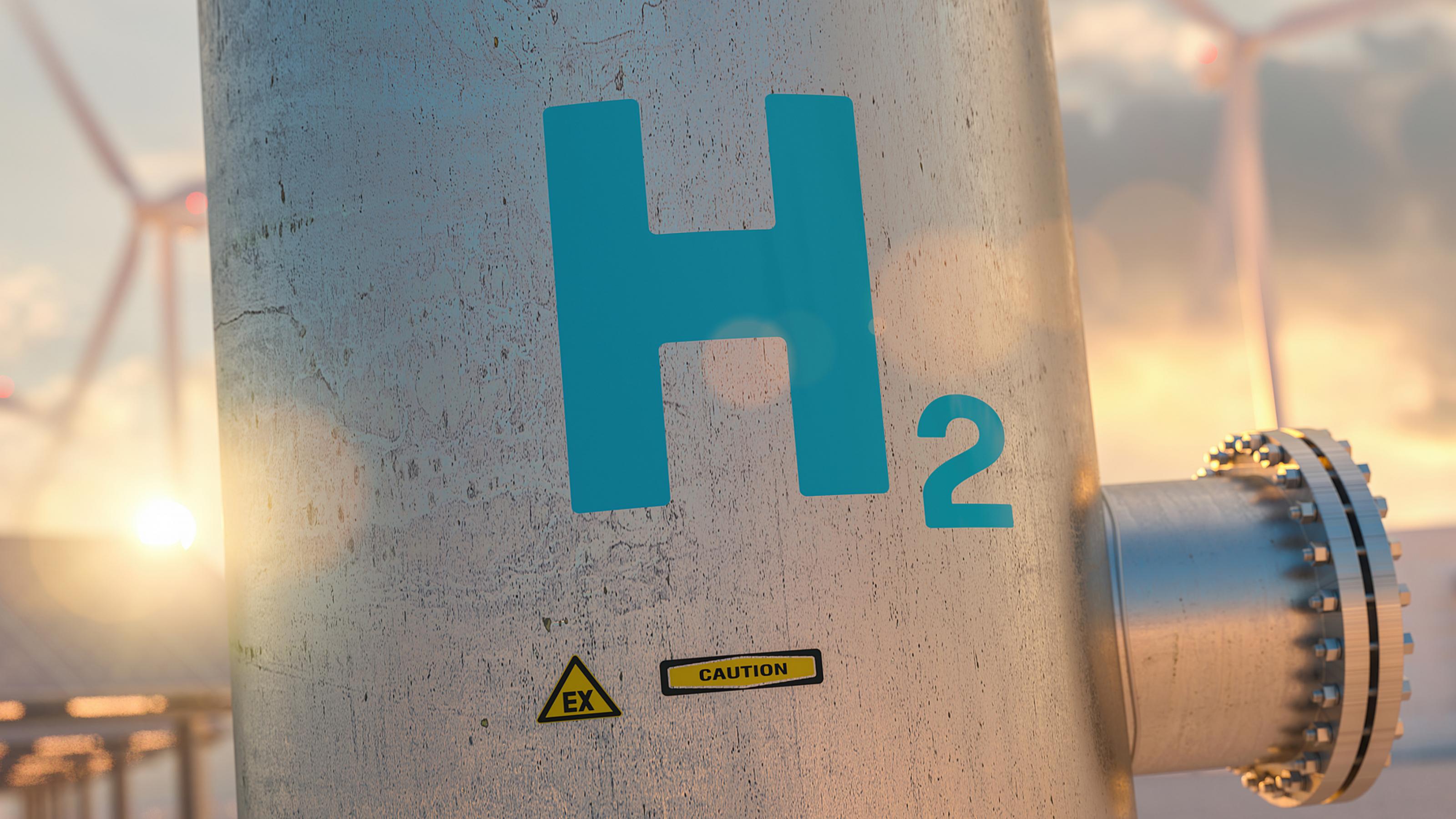 Eine Leitung mit der Aufschrift H2, dahinter Windräder.