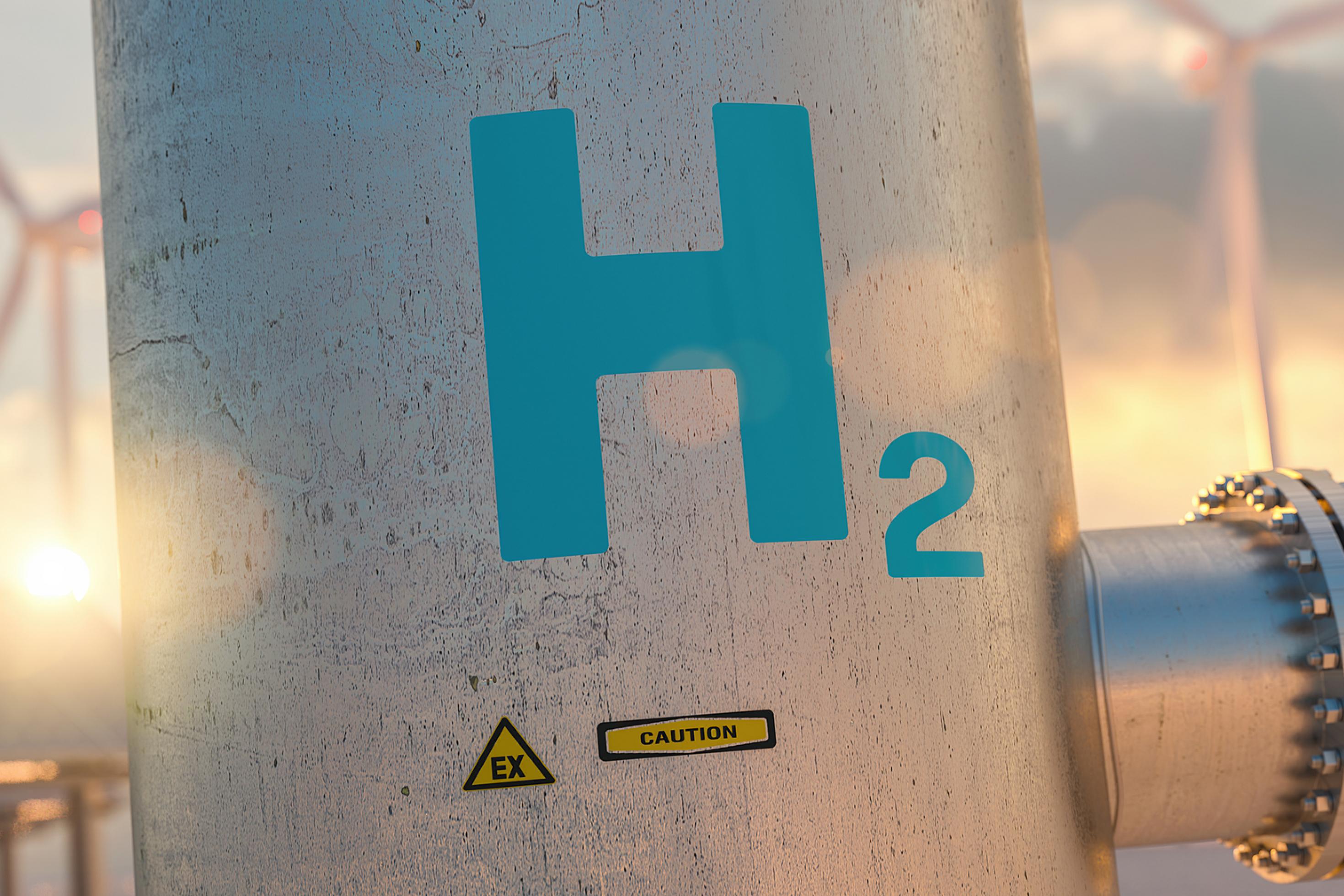 Eine Leitung mit der Aufschrift H2, dahinter Windräder.