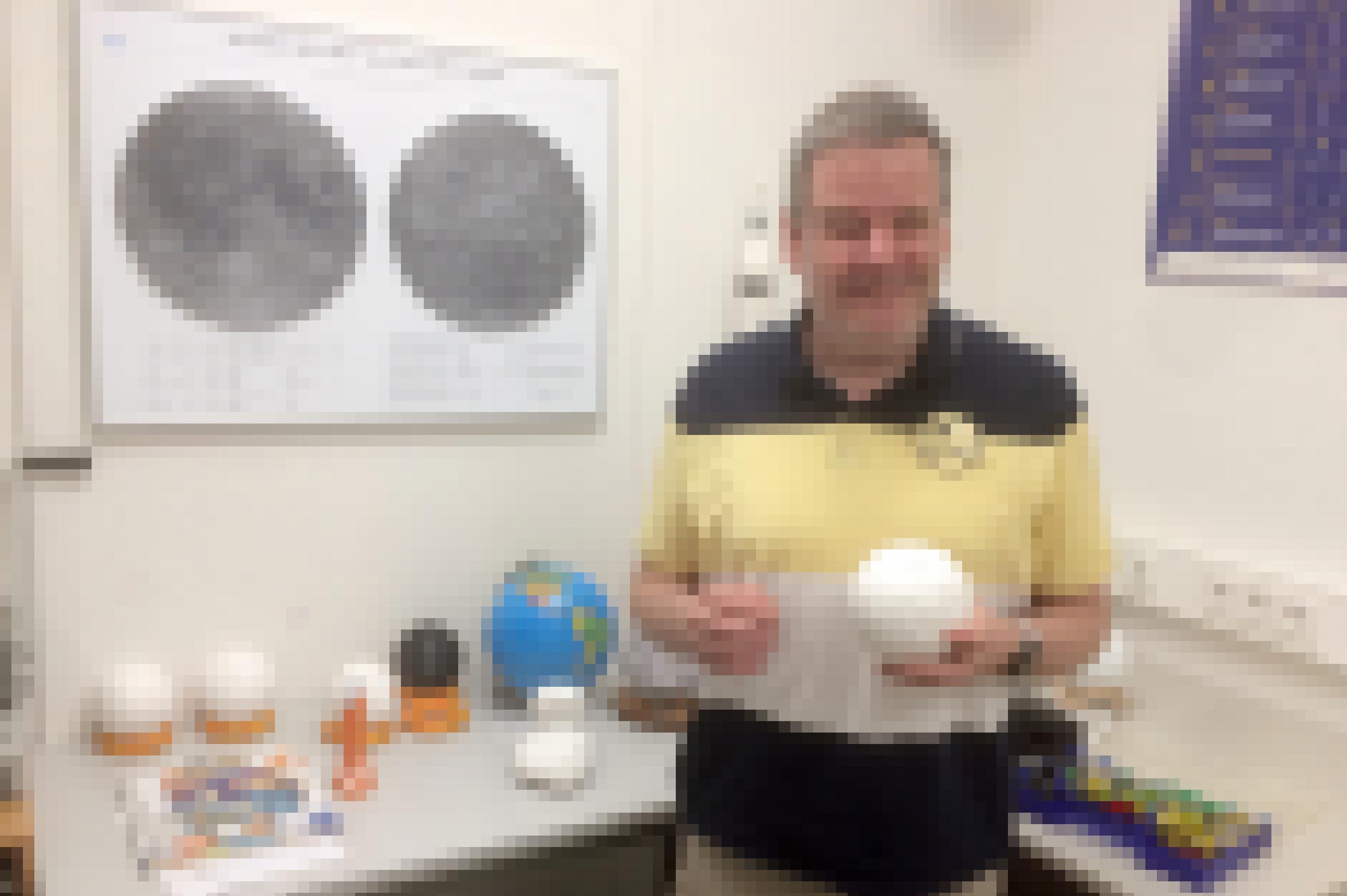 Gerhard Jaworek hält eine weiße Kugel (ein 3D-gedruckter Planet), hinter ihm liegen auf einem Tisch allerlei Globen und der Komet 67P als Modell