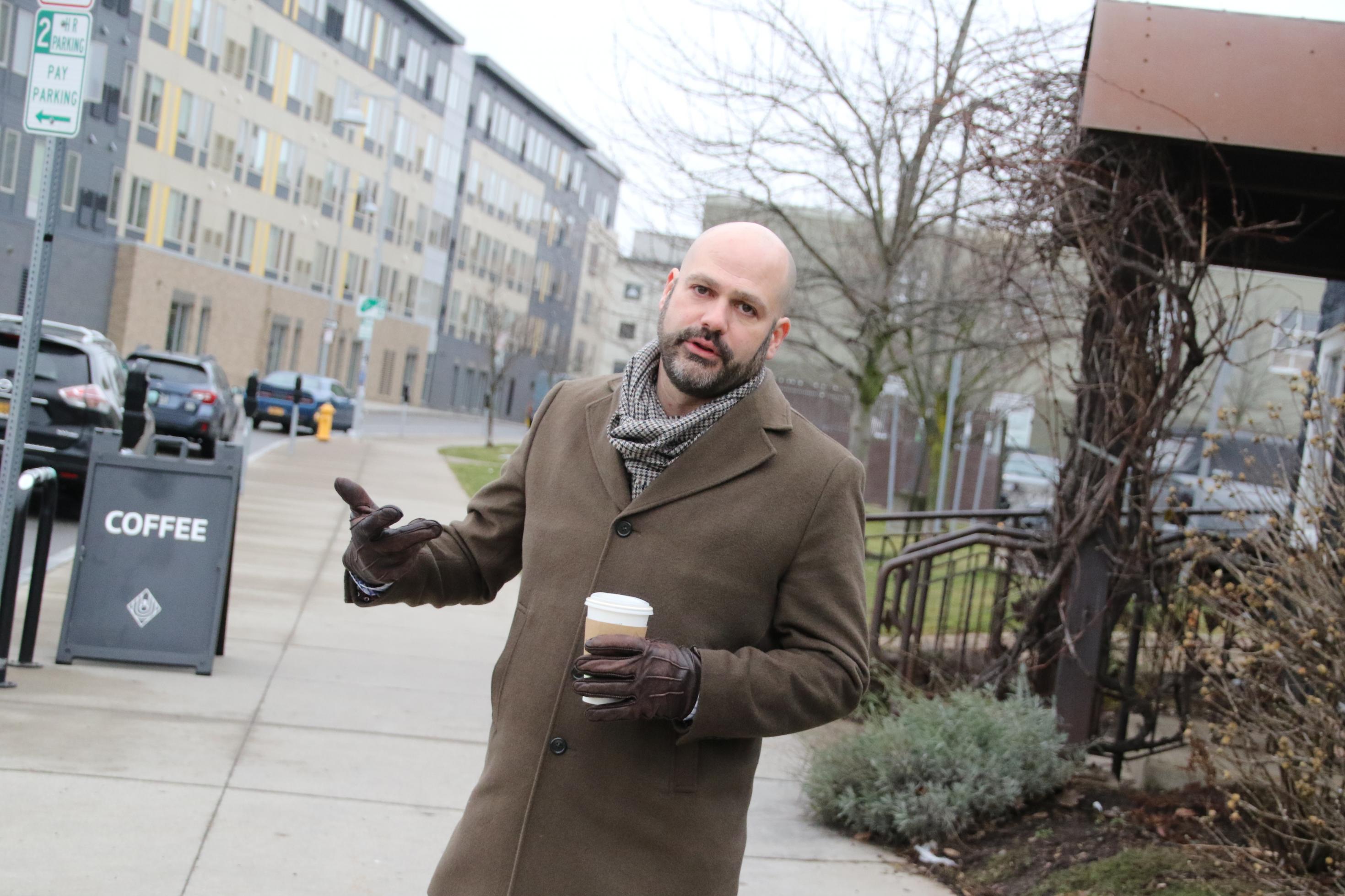 Stadtplaner Erik Frisch steht auf dem Bürgersteig mit einem coffee-to-go.