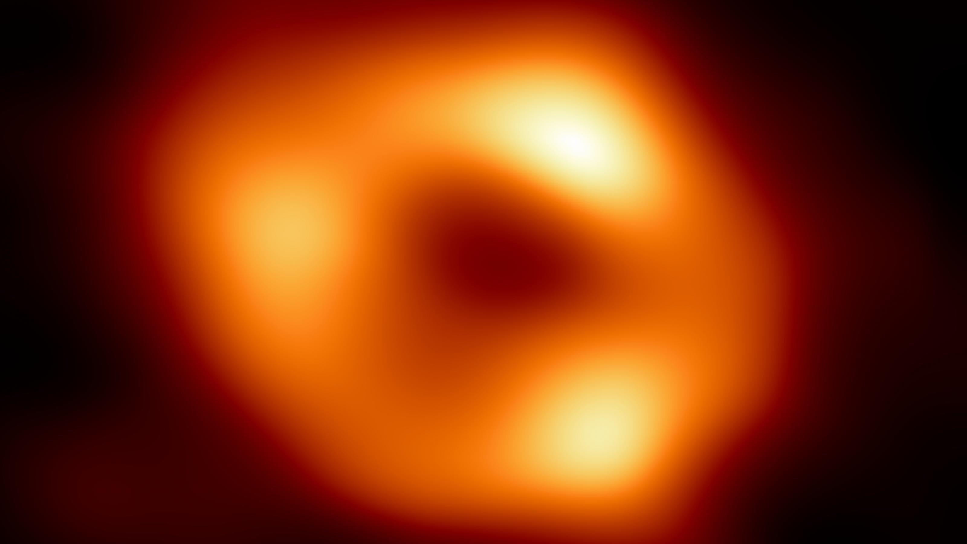 Das Bild zeigt einen orangefarbenen Ring mit asymmetrischen Verdickungen vor schwarzem Hintergrund.
