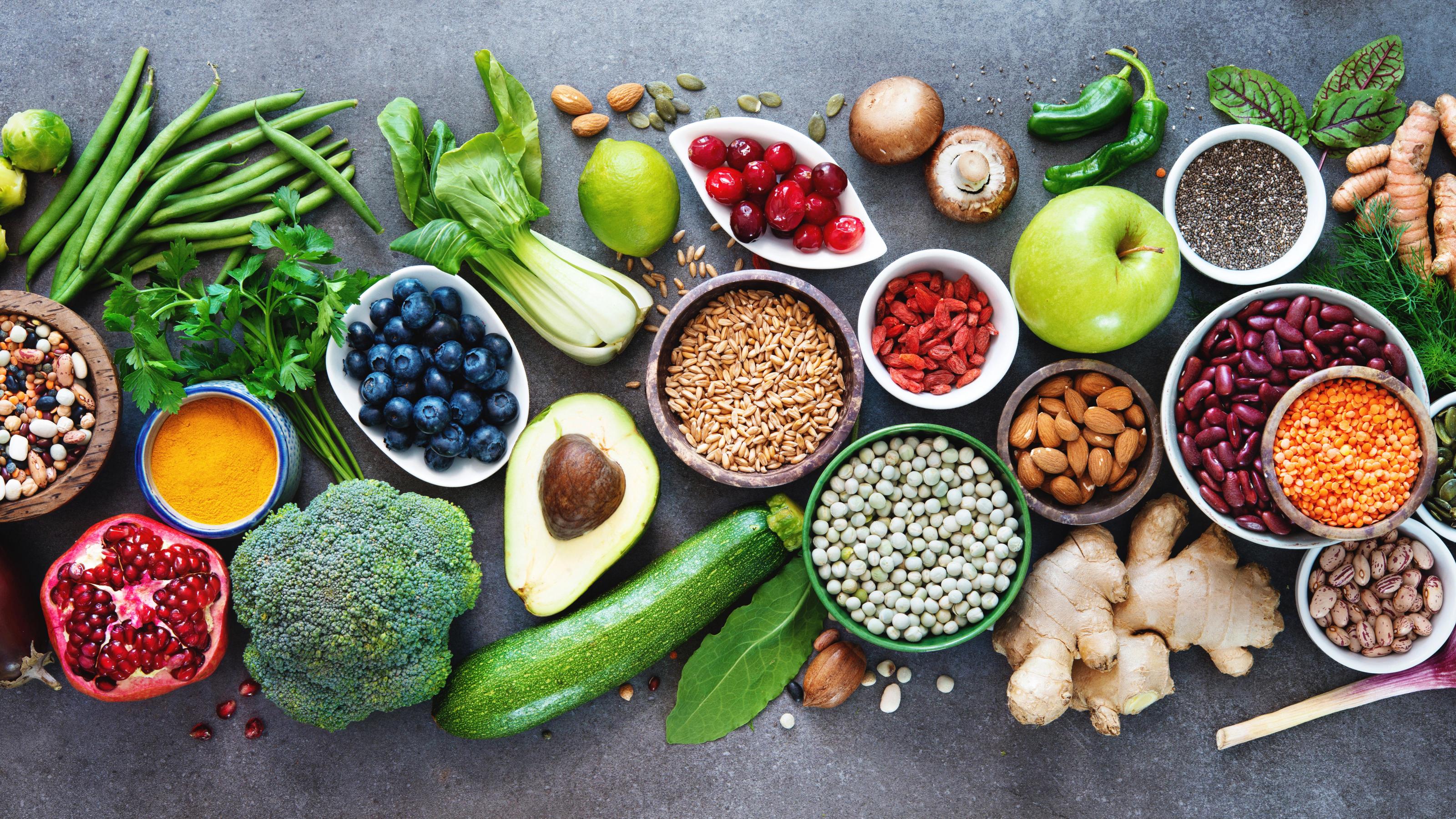 Foto einer breiten Auswahl an gesunden Nahrungsmitteln, darunter Früchte, Gemüse und Saaten.