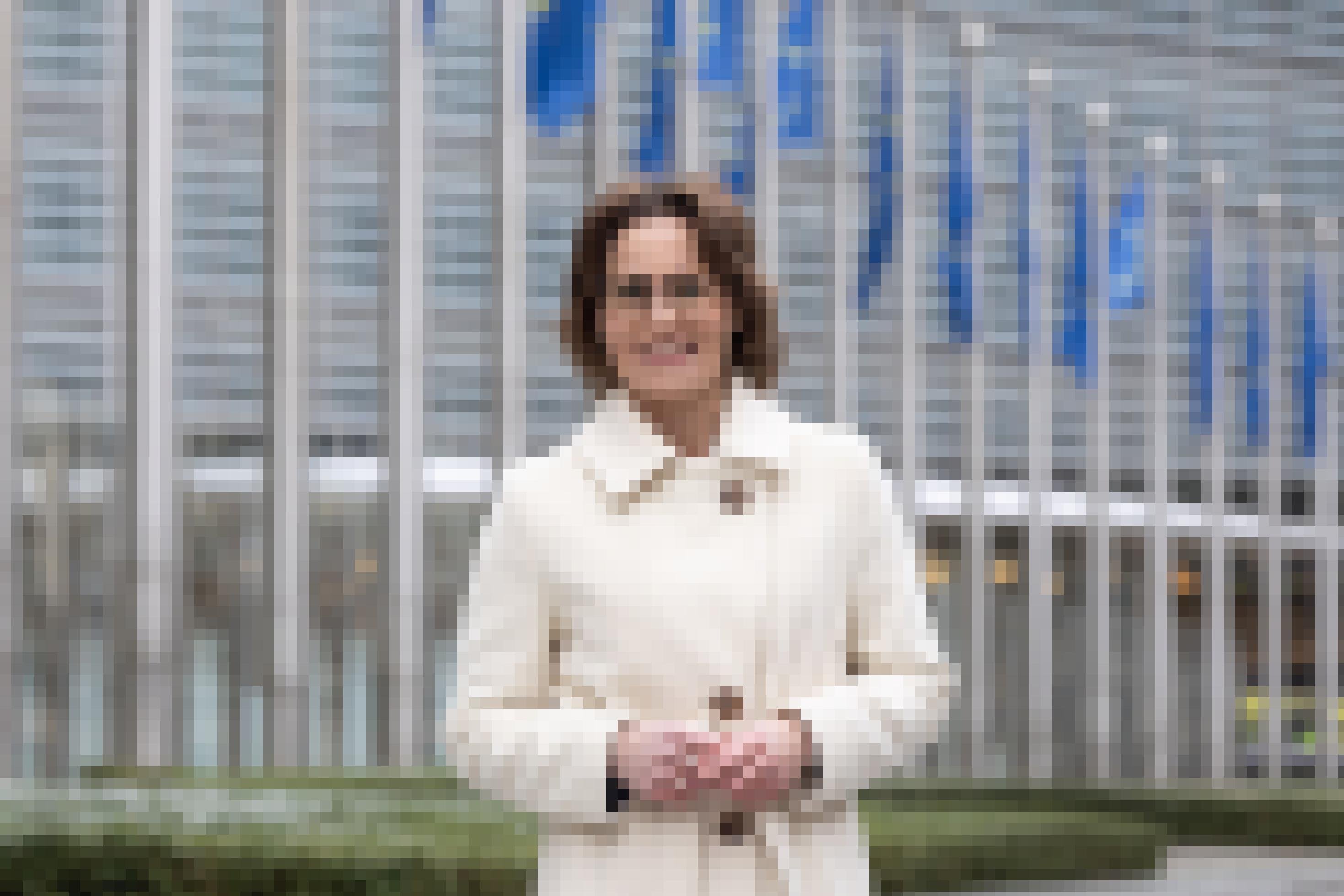 Jessika Roswall vor EU-Fahnen in weißem Mantel.