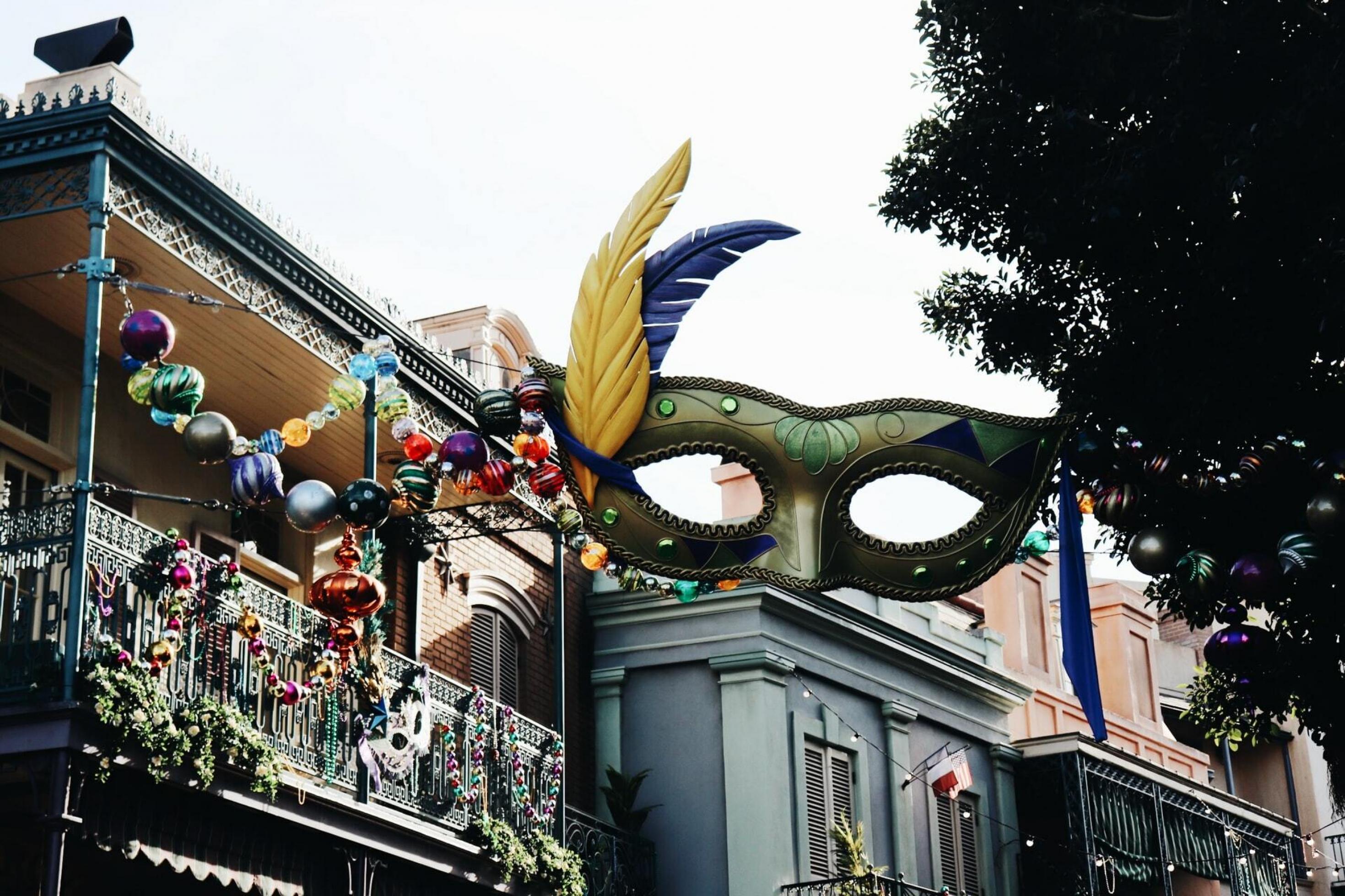 Details von Balkonbalustraden im Stil von New Orleans nachgebaut in Disneyland gesehen aus einem Winkel von unten mit einer eleganten Karnevalsmaske im Vordergrund