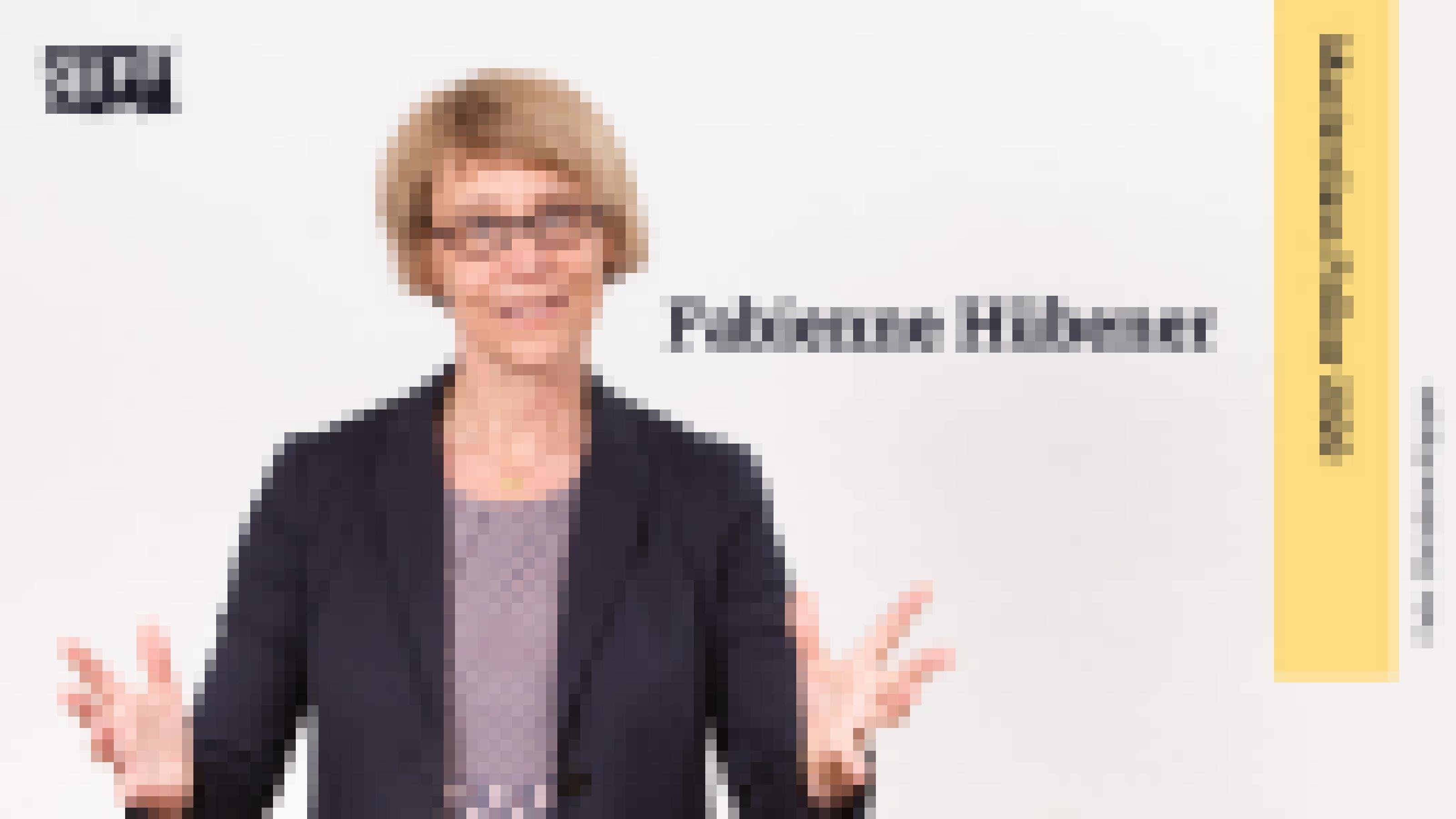 Eine blonde Frau mit Brille schaut in die Kamera und breitet ihre Arme nach vorne aus. Rechts neben ihr steht der Name Fabienne Hübener. Daneben befindet sich ein Banner mit der Aufschrift „Masterclass Fellow 2020“.