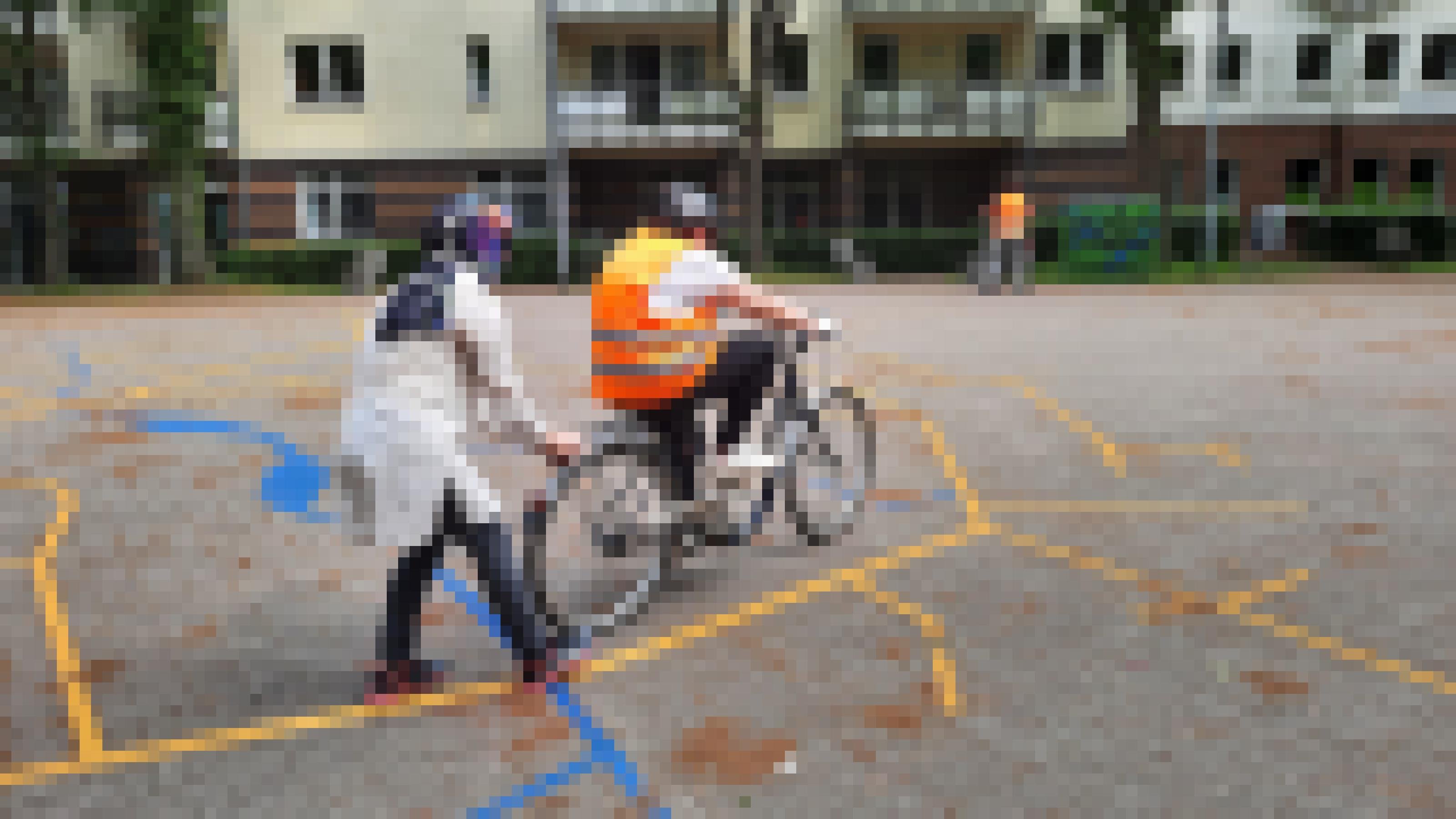 Eine Frau hält den Gepäckträger eines Fahrrads fest auf dem eine andere Frau sitzt.