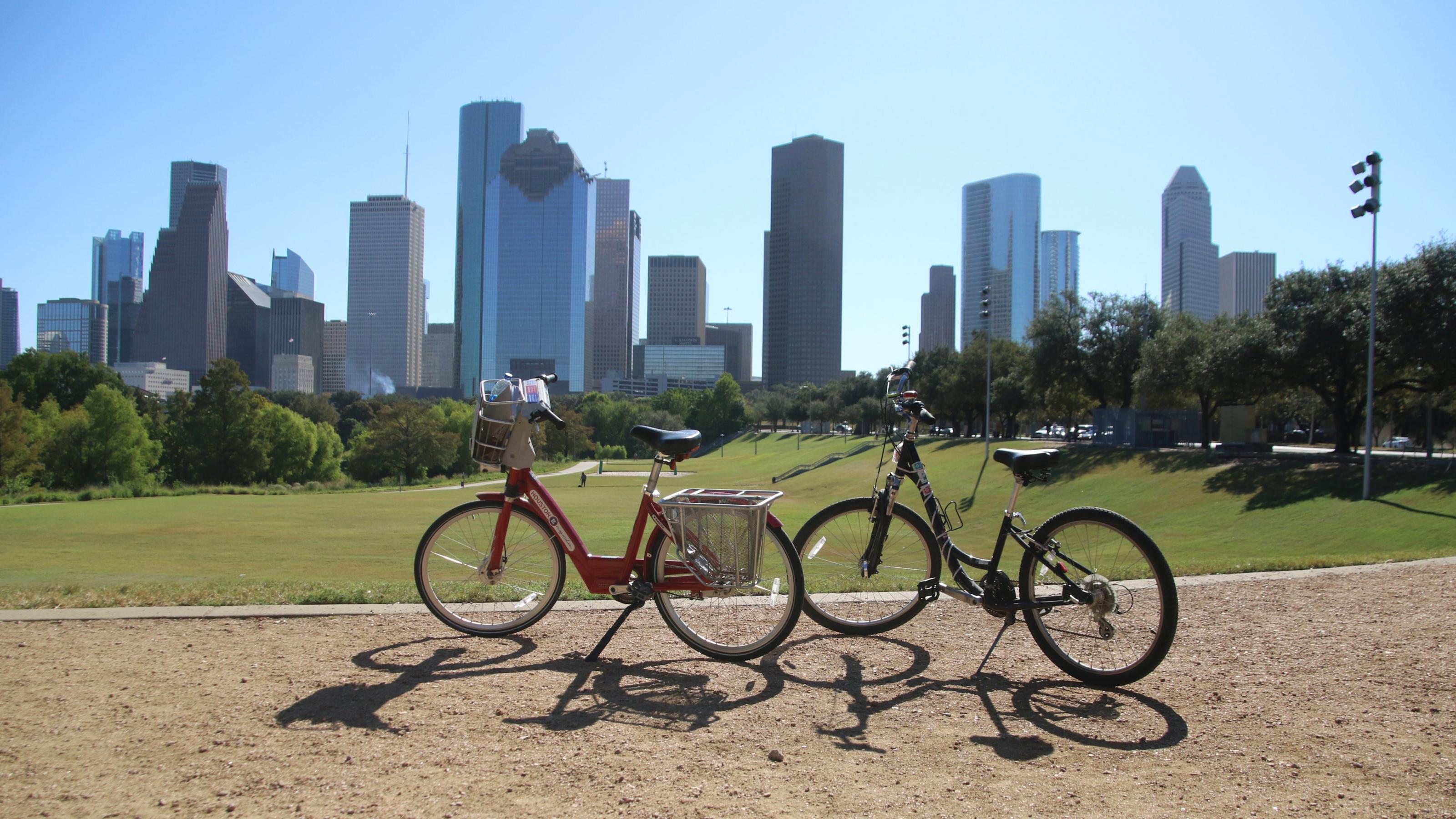Zwei Fahrräder stehen in einem Park in Houston, im Hintergrund Hochhäuser.