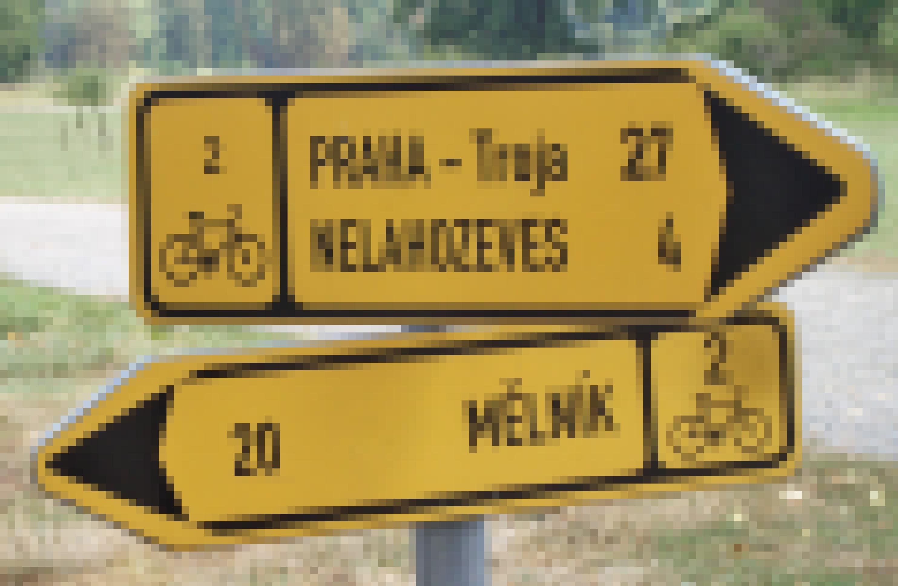 Zwei Hinweisschilder für Radfahrende weisen in entgegengesetzte Richtungen: Das eine gen Mělník, das andere gen Prag.