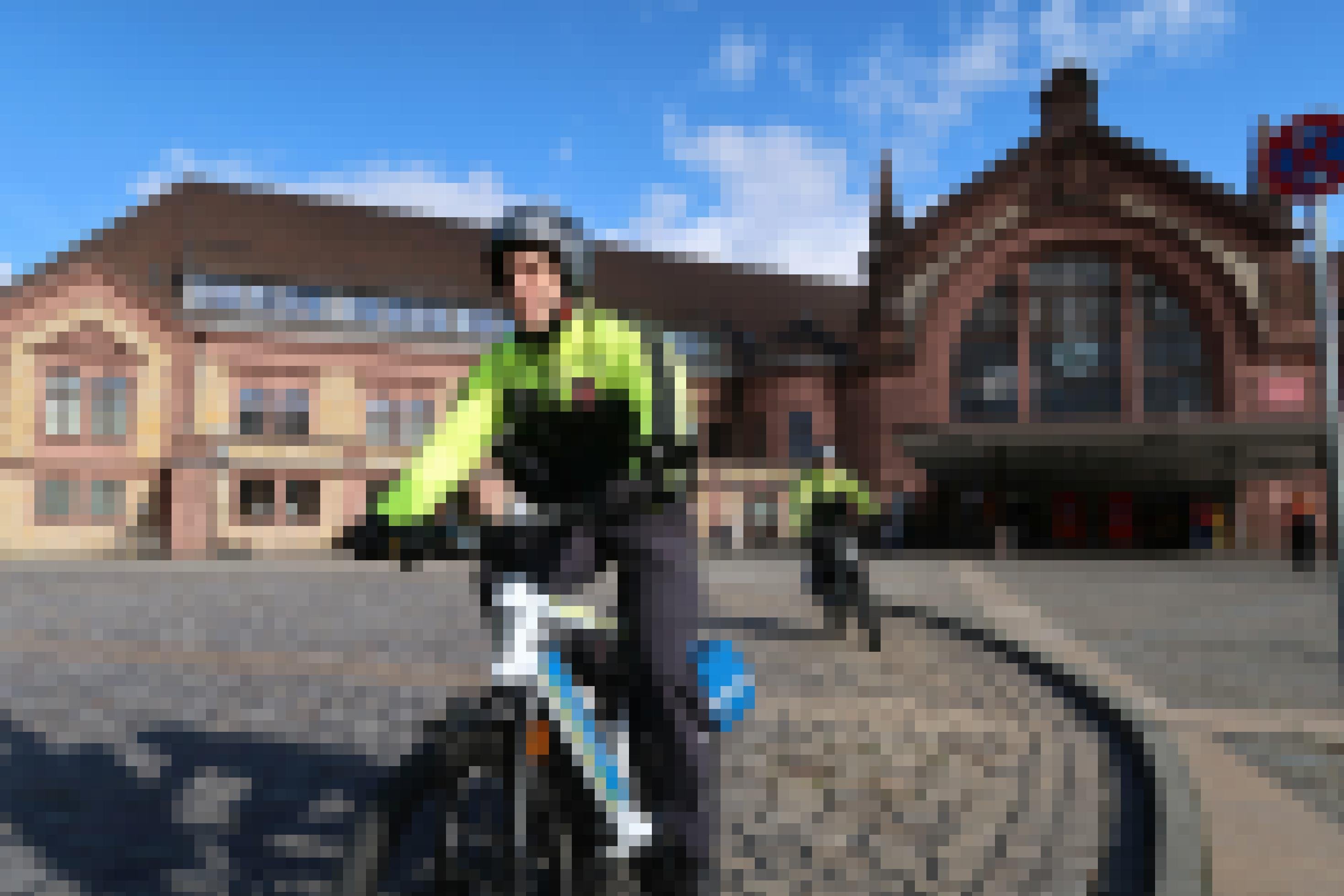 Zwei Fahrradpolizisten fahren vor einem Bahnhof Streife.