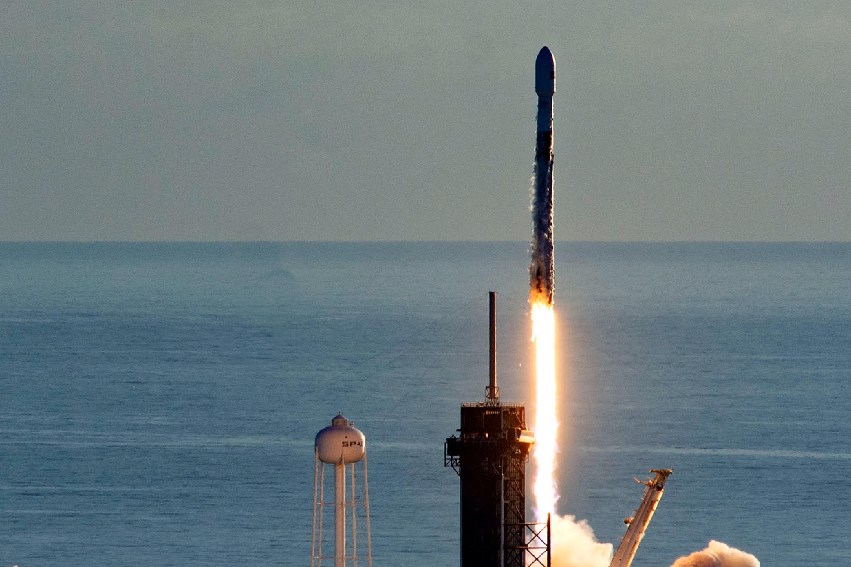 Die Rakete Falcon 9 hebt in Florida vor einem blau schimmernden Atlantik ab.