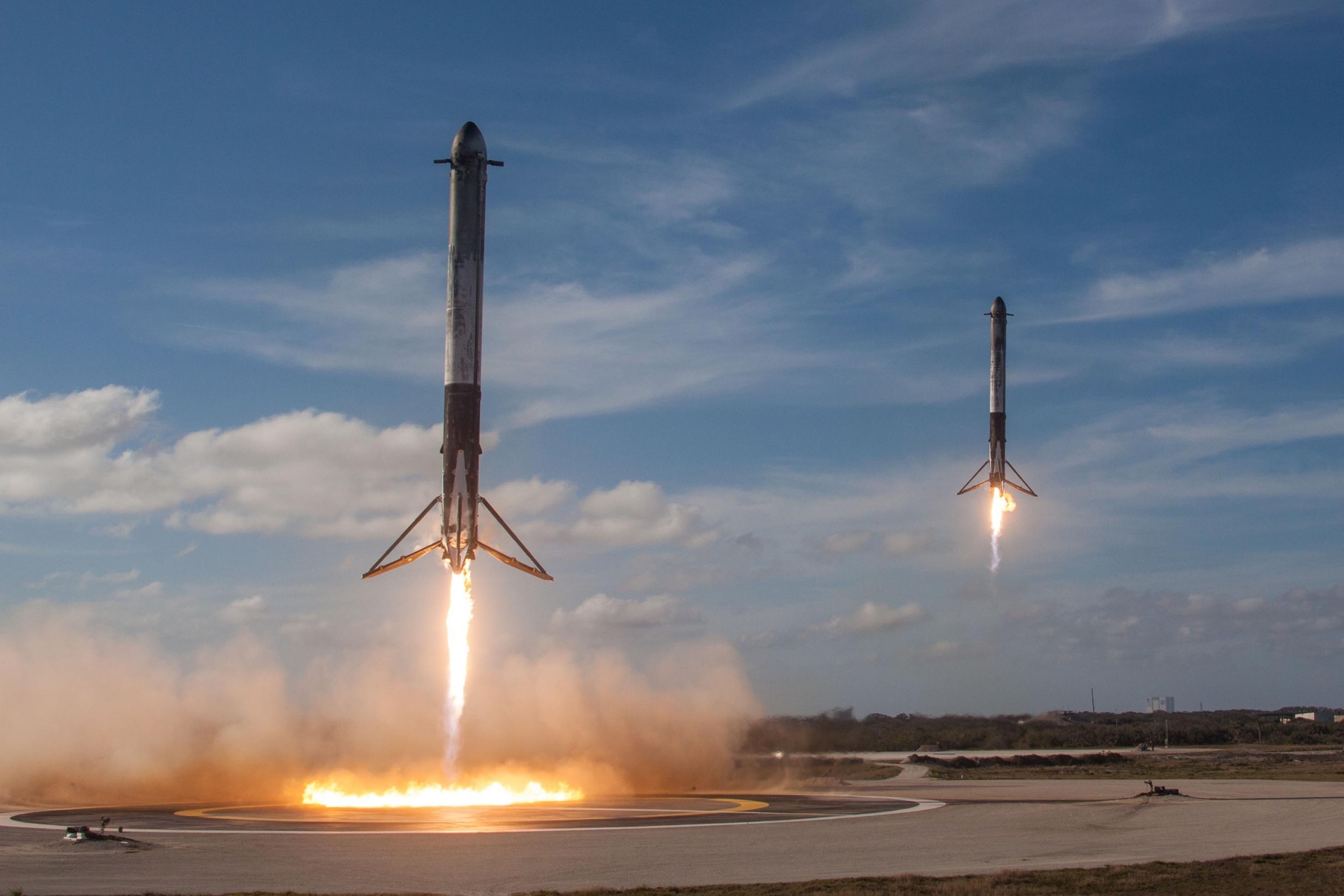 Zwei Booster landen auf einem Asphaltfeld.