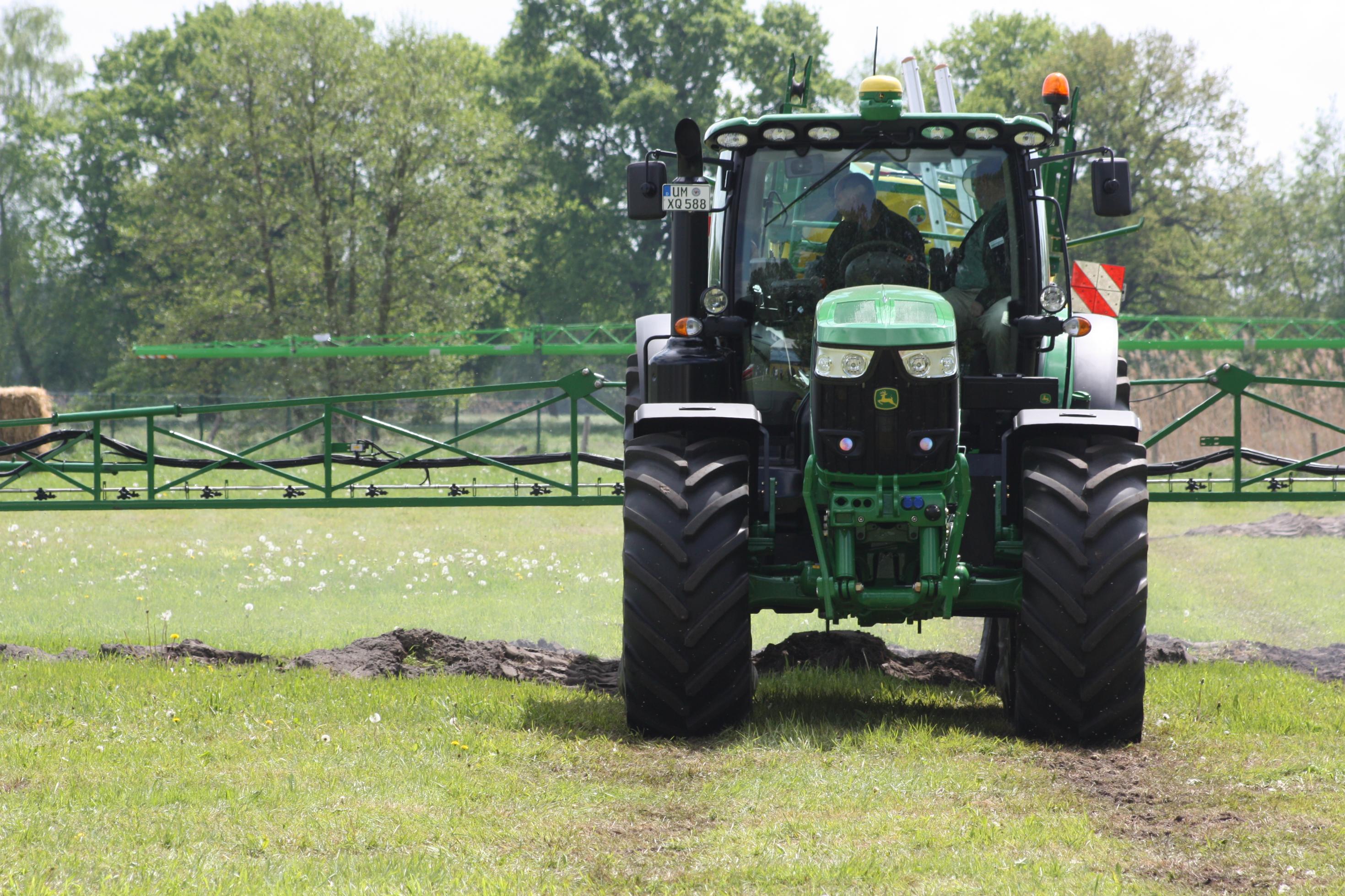 Ein Traktor mit aufgesattelter Feldspritze zur Unkrautbekaempfung faehrt auf den Fotografen zu