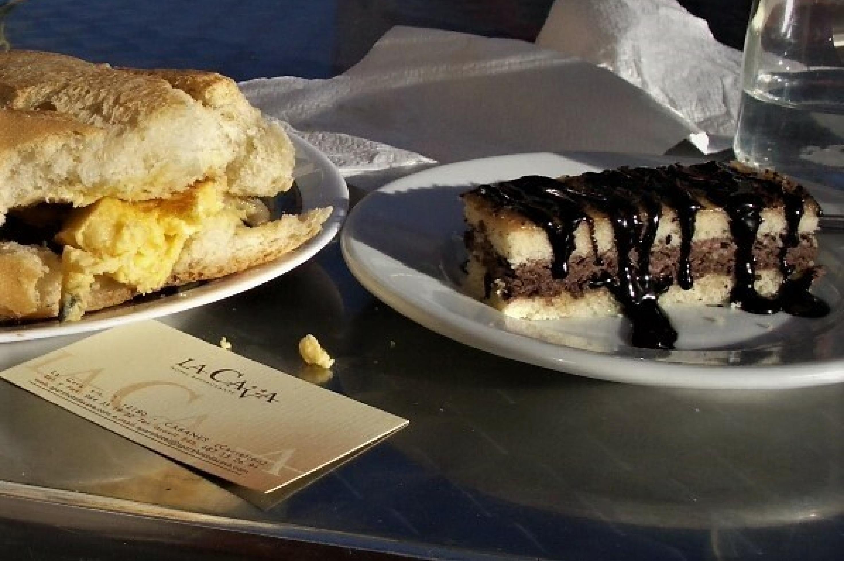 Auf einem Teller liegt eine Kuchenschnitte, die mittig eine schokohaltige Schaummasse enthält und mit einer dickflüssigen Schokosoße übergossen ist.
