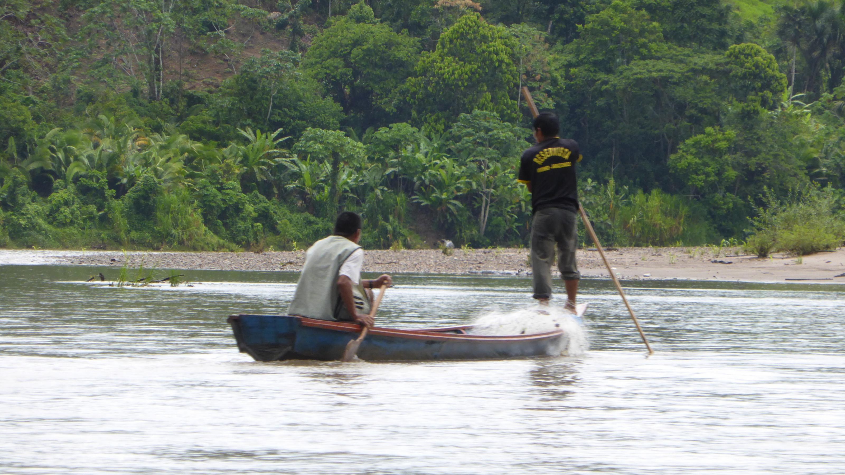 Zwei Fischer auf einem Boot holen ein Netz ein.