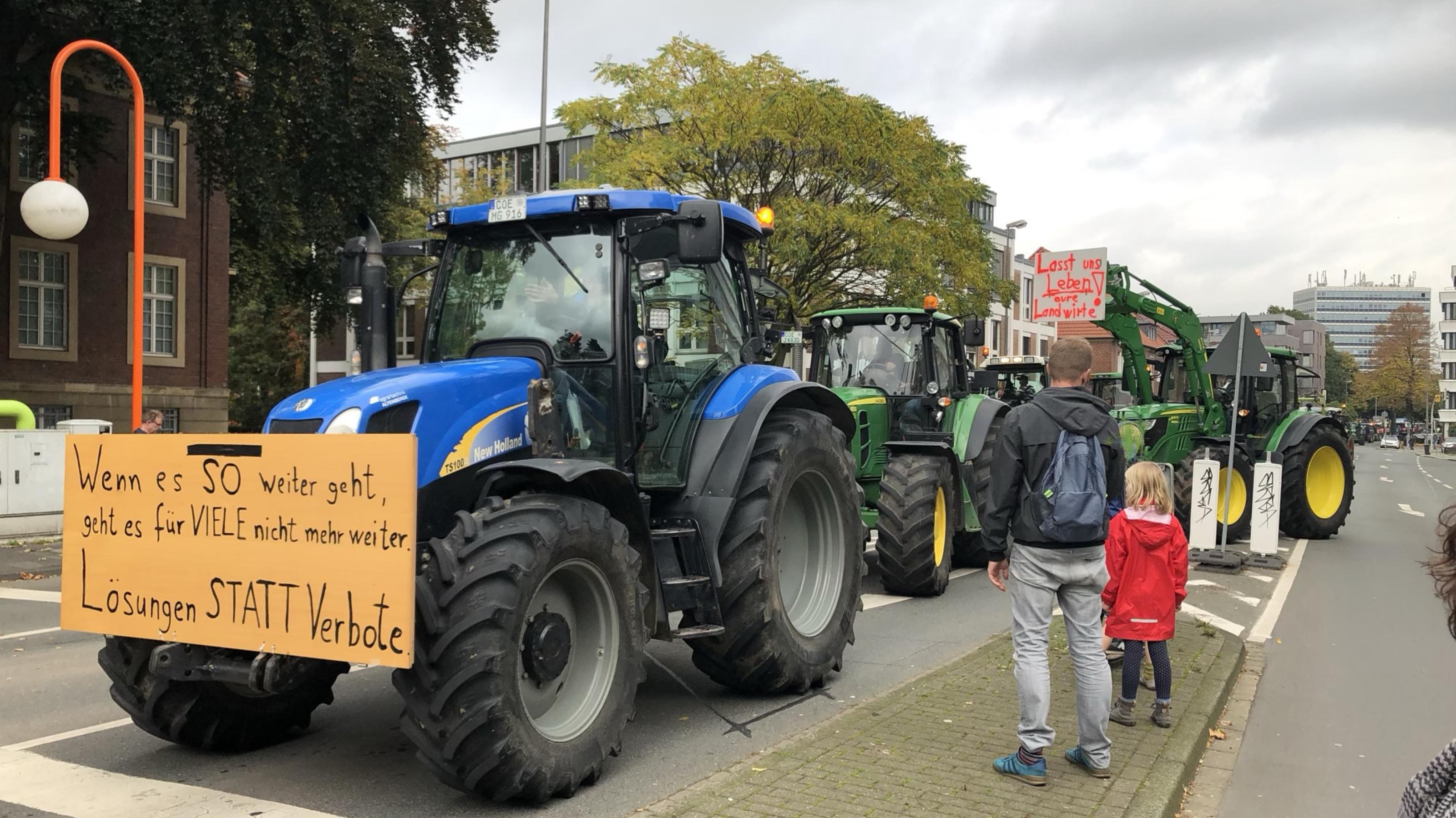 Trecker fahren auf einem Bauernprotest in Münster. 23.10.2019. Ein Mann schaut sich mit seinem Kind das Geschehen vom Straßenrand aus an.