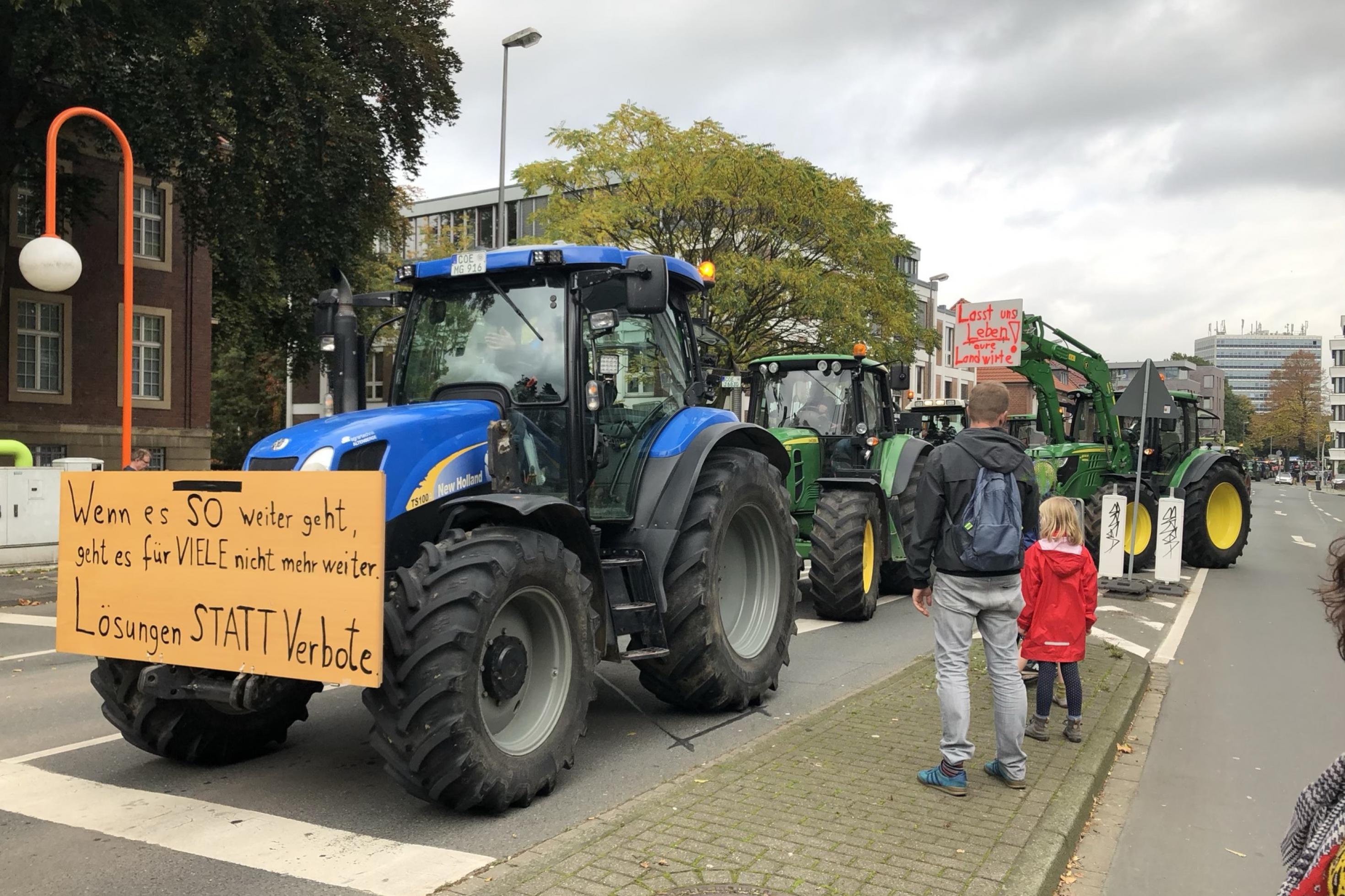 Trecker fahren auf einem Bauernprotest in Münster. 23.10.2019. Ein Mann schaut sich mit seinem Kind das Geschehen vom Straßenrand aus an.