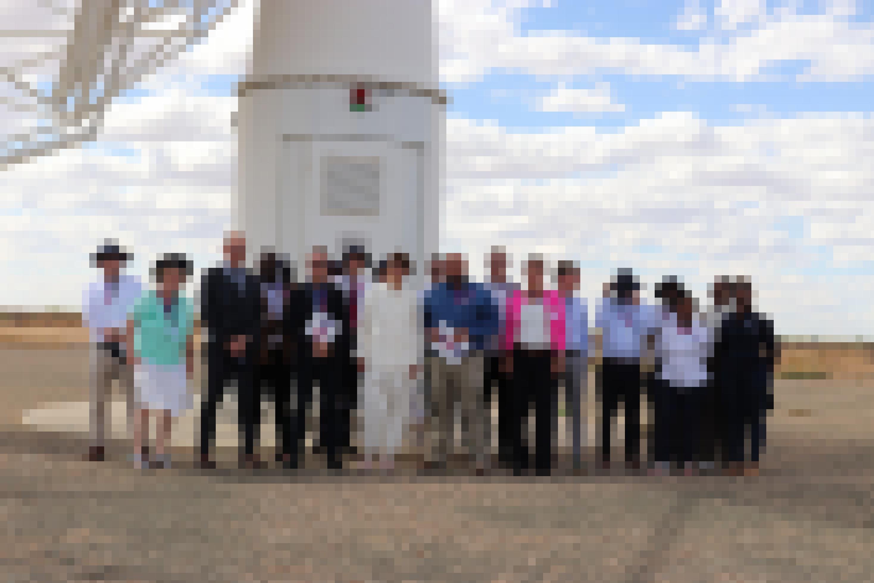 Eine Gruppe von Forschern und Behördernvertretern steht vor dem Sockel eines Radioteleskops.