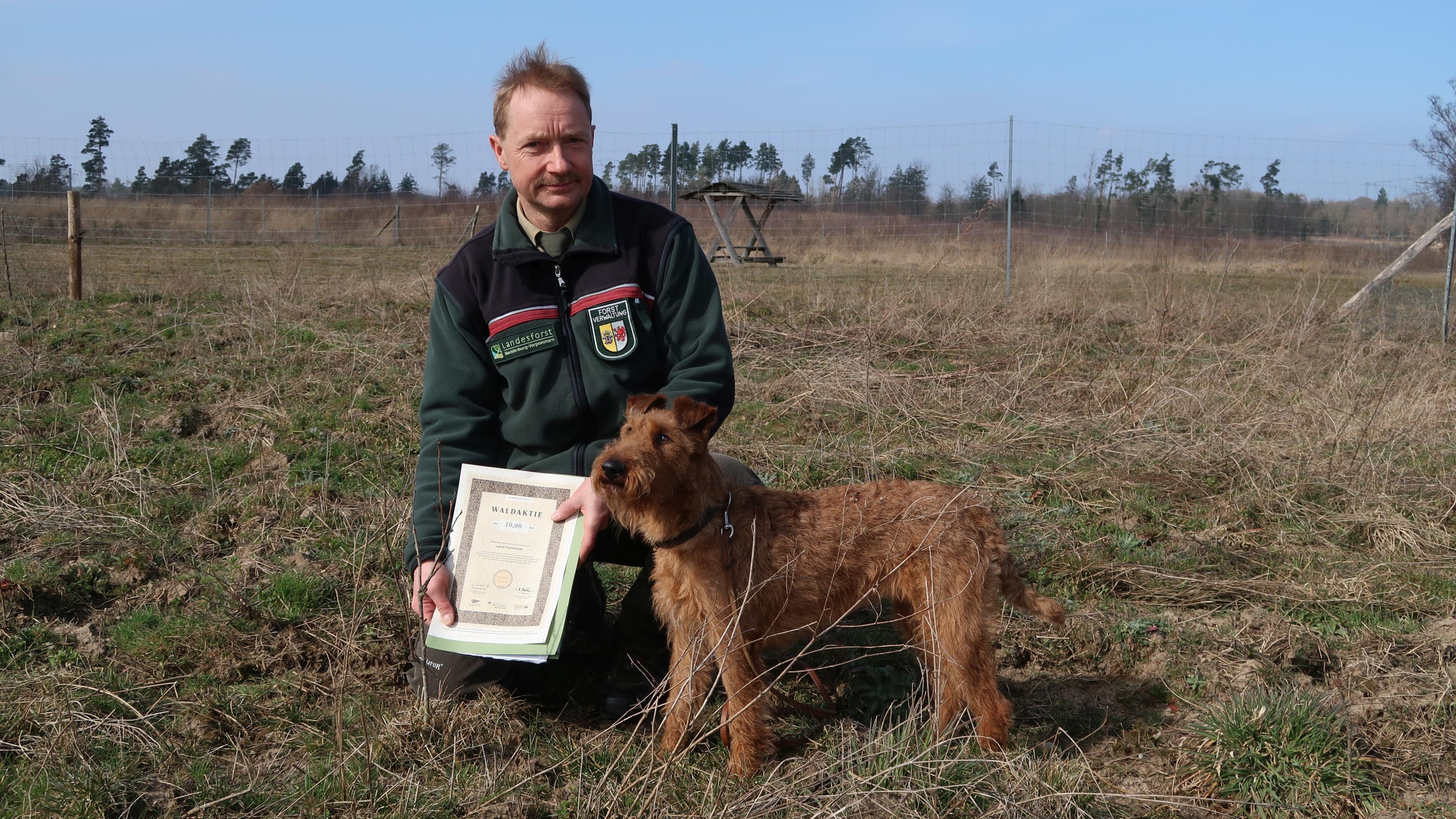 Forstamtsleiter Bernd Pöppel hält eine Waldaktie in der Hand