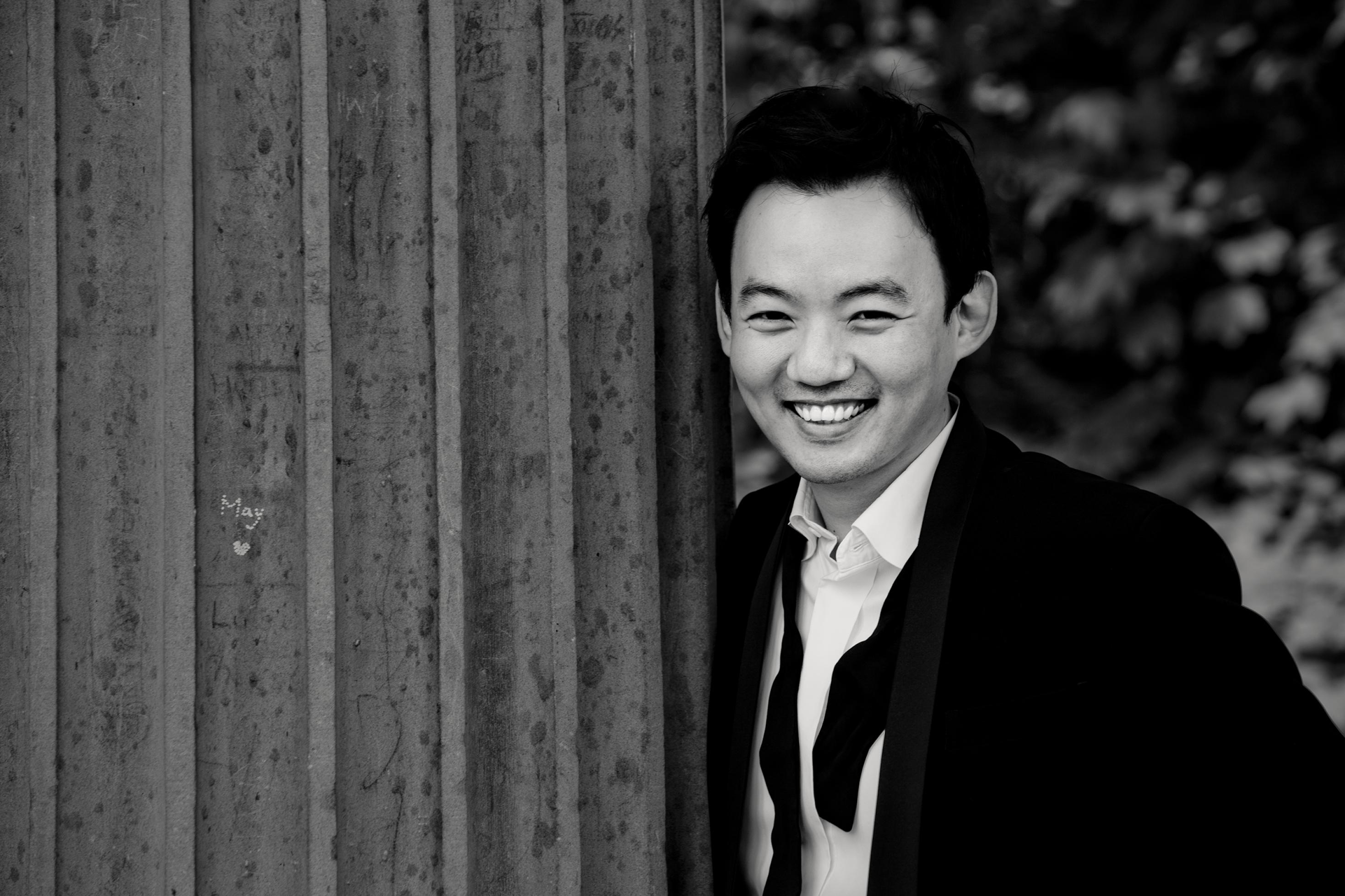 Der Pianist William Youn steht lachend, draußen vor einer Wand