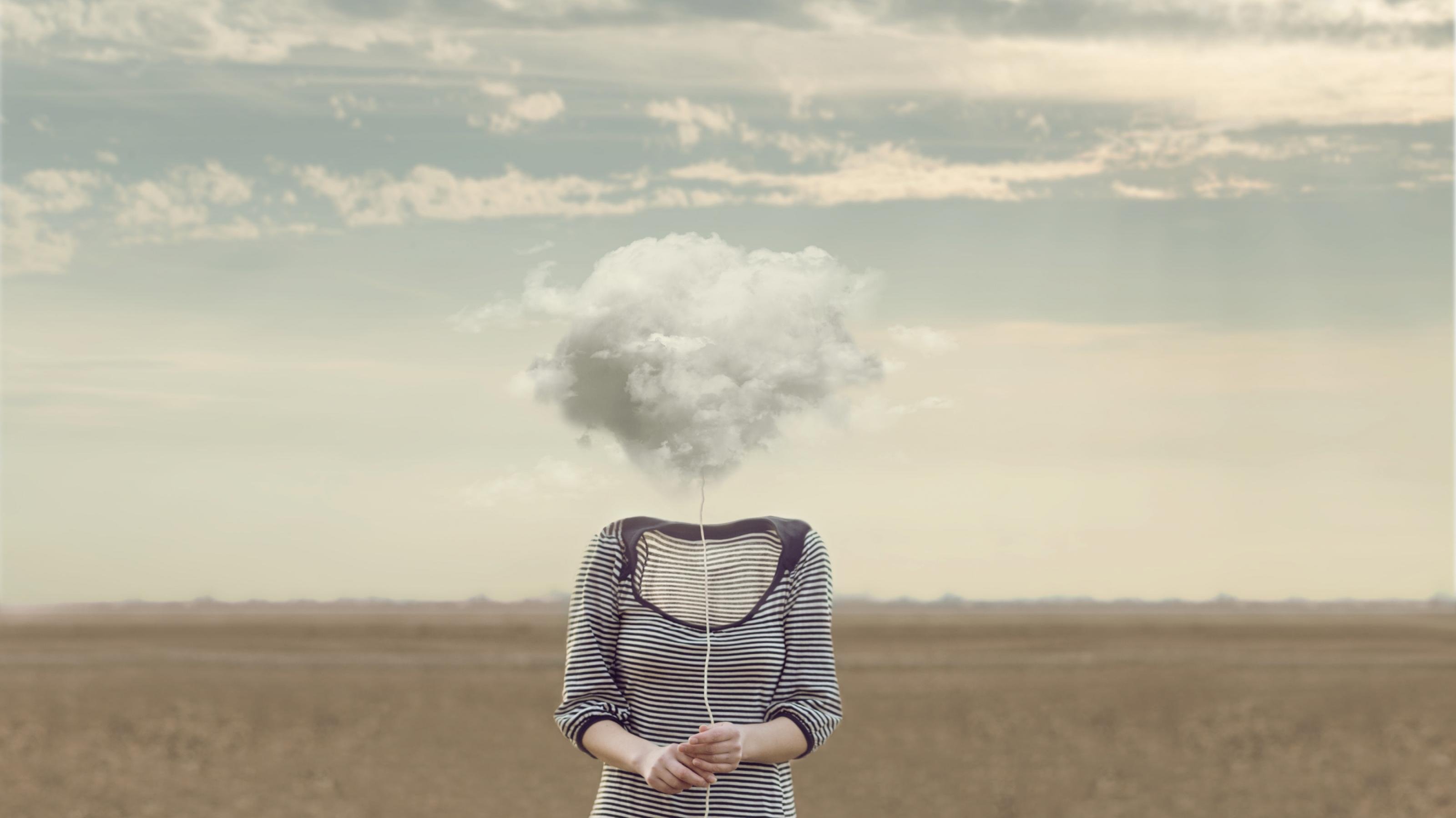 Eine Frau in einem grau-weiß gestreiften Kleid, steht ohne Kopf in einer Wüste. Anstelle ihres Kopfes ist eine Wolke abgebildet.