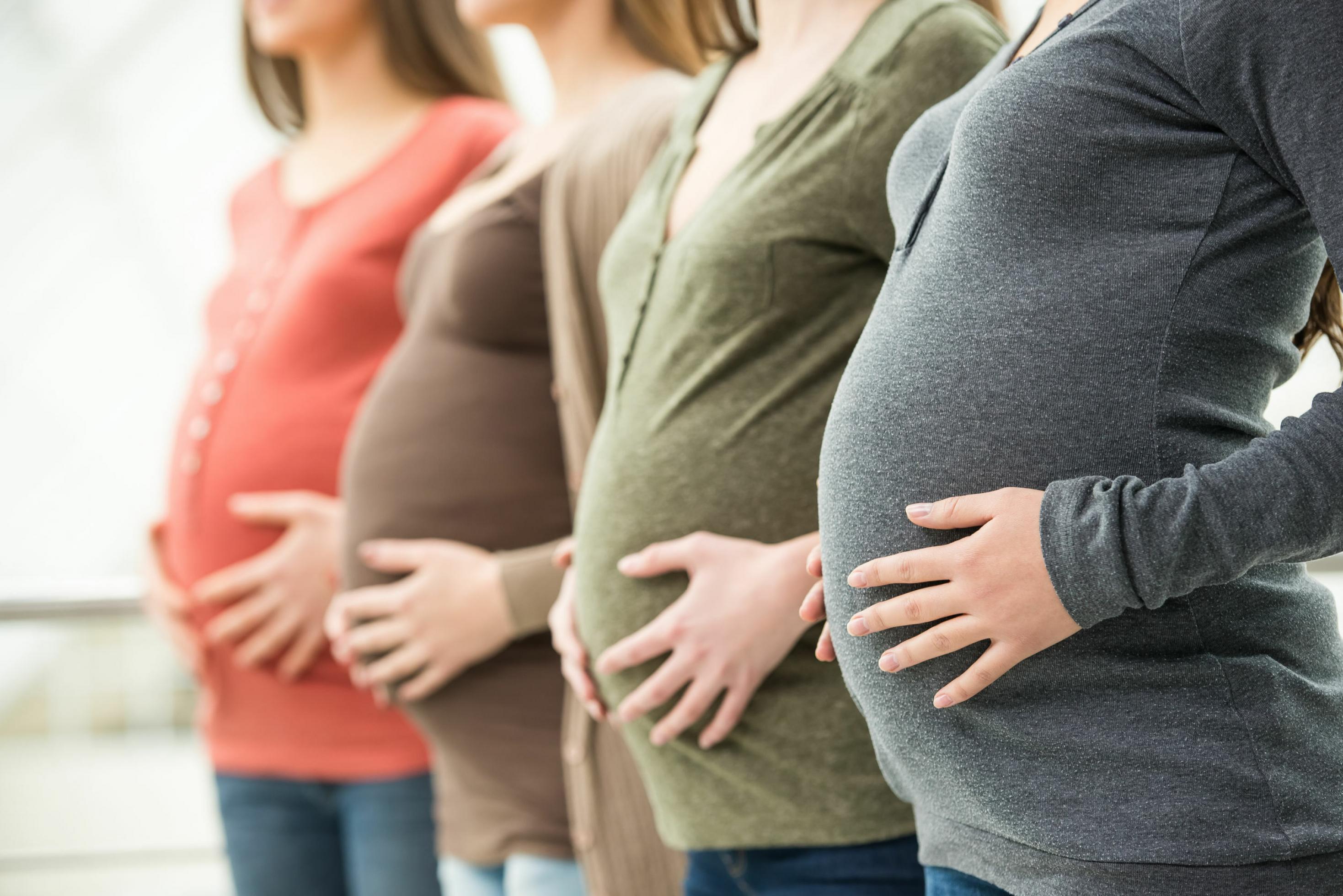 Auf dem Bild sind die Oberkörper von mehreren, hintereinander stehenden schwangeren Frauen zu sehen, die ihre Hände auf den Bauch halten. Das Foto soll Schwangerschaft und Fruchtbarkeit symbolisieren. Forscherïnnen aus Leipzig fanden jetzt heraus, dass Frauen, die eine bestimmte Genvariante – einen Rezeptor für das Hormon Progesteron – von Neandertalern geerbt haben, mehr Kinder gebären